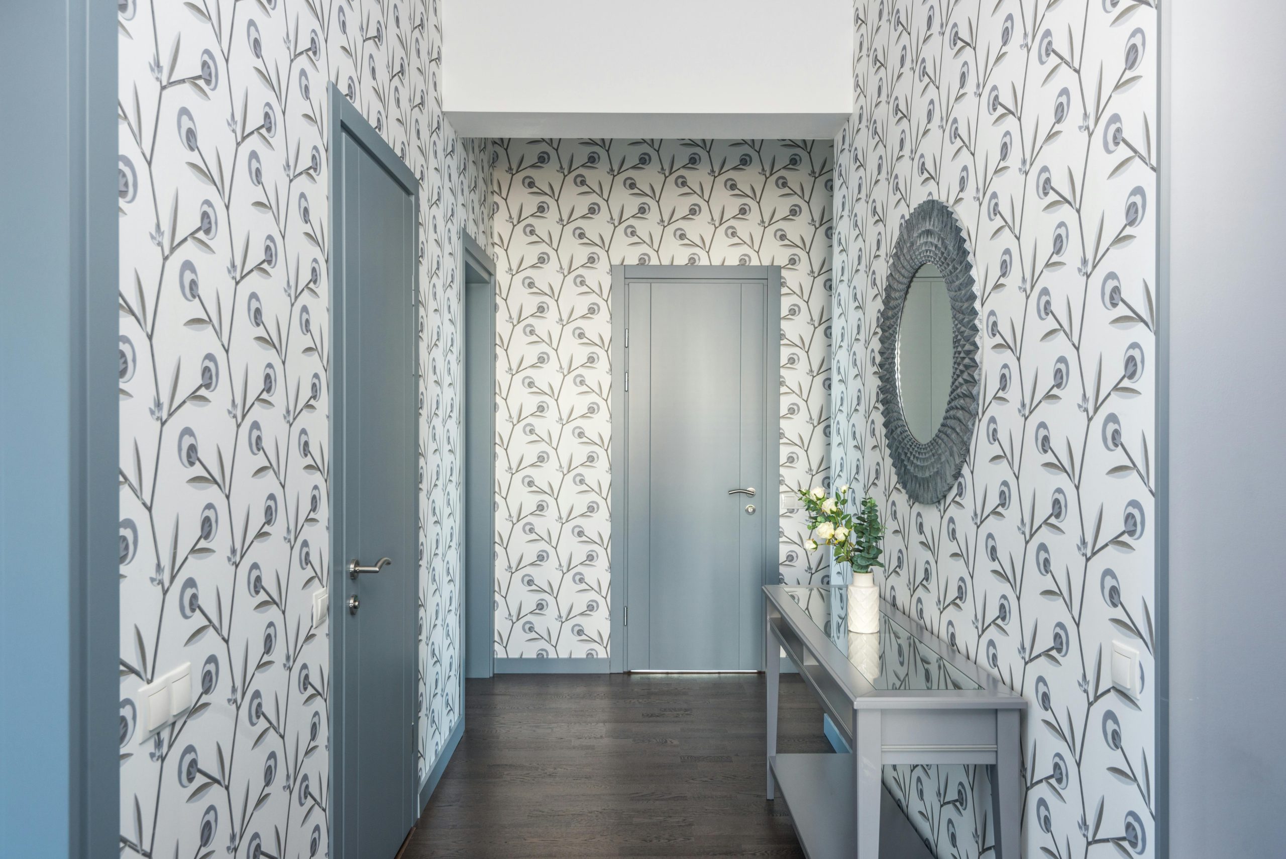 A stylish hallway featuring floral wallpaper, a console table, and a decorative mirror.