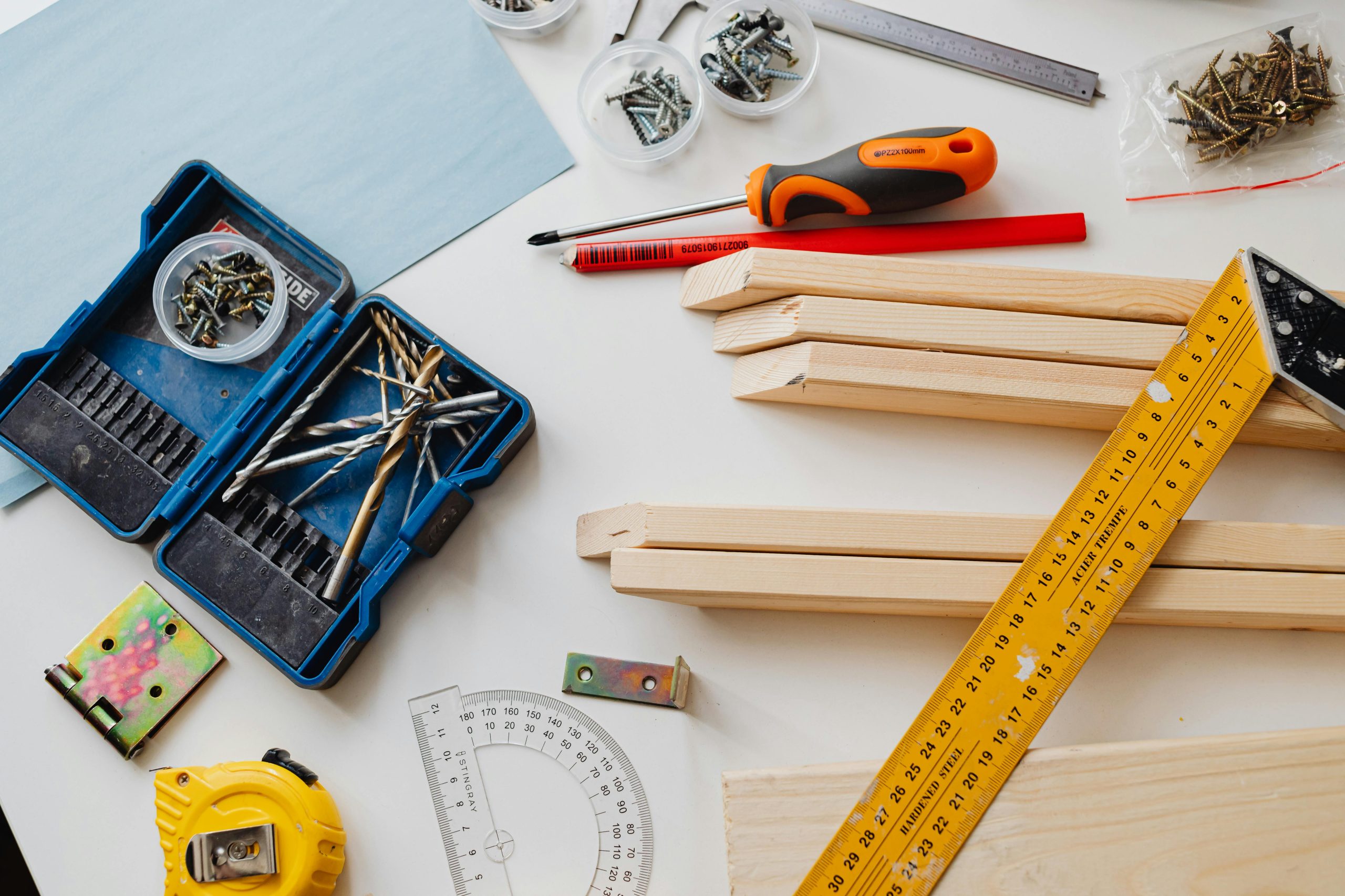 A top view of various woodworking tools and materials on a white table.