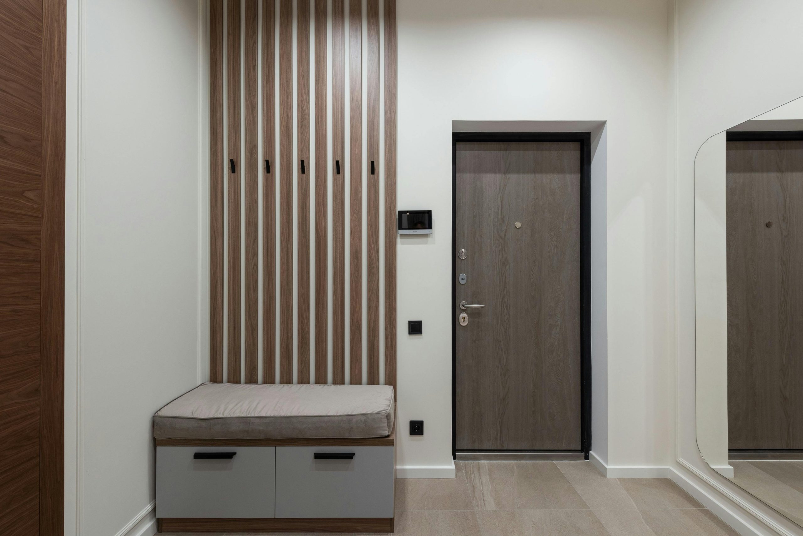 Stylish entrance area with wooden panels, seating, and a mirror.