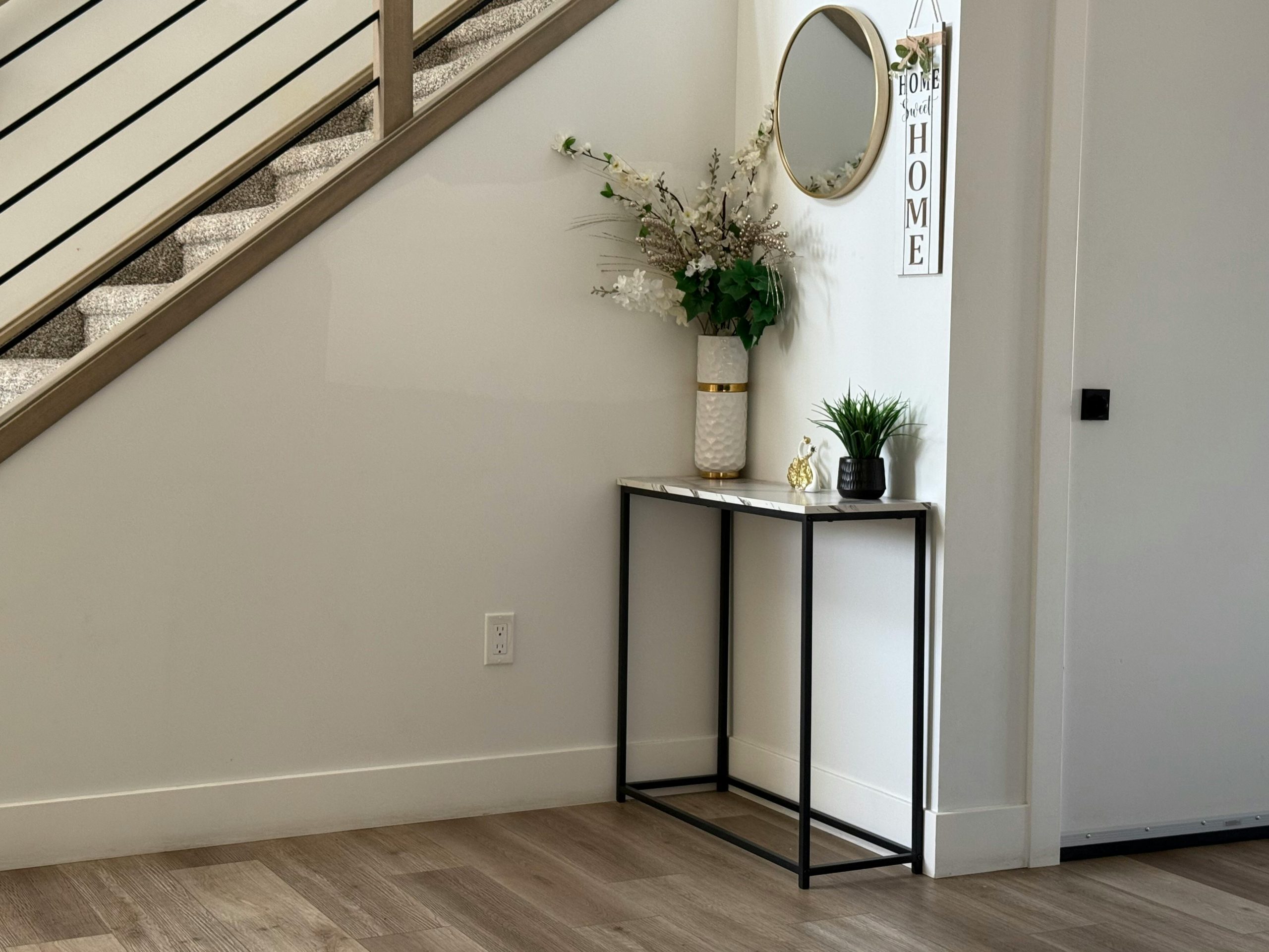 Stylish entryway with minimalist decor, modern staircase, and elegant plants.