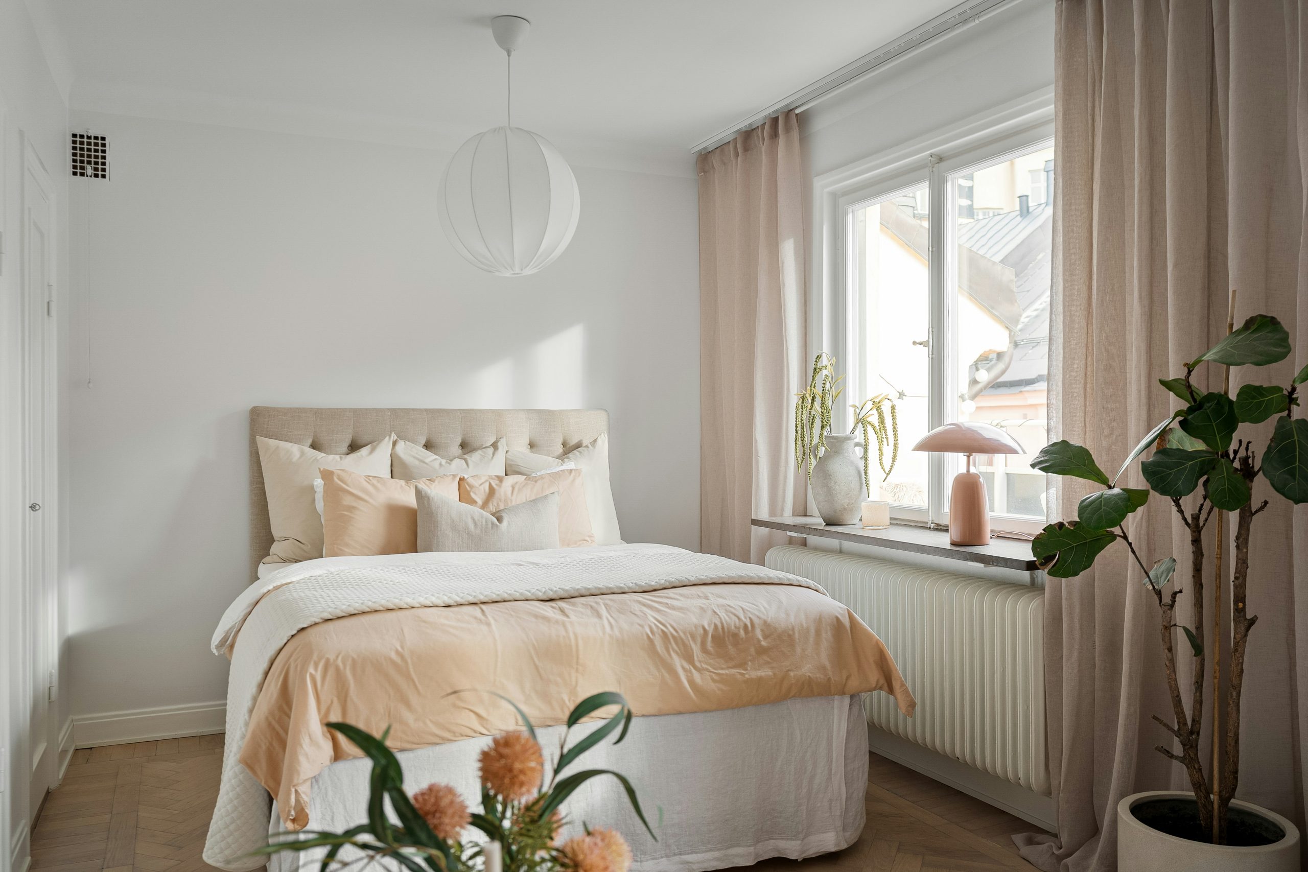 A bedroom with a bed and a plant in the corner