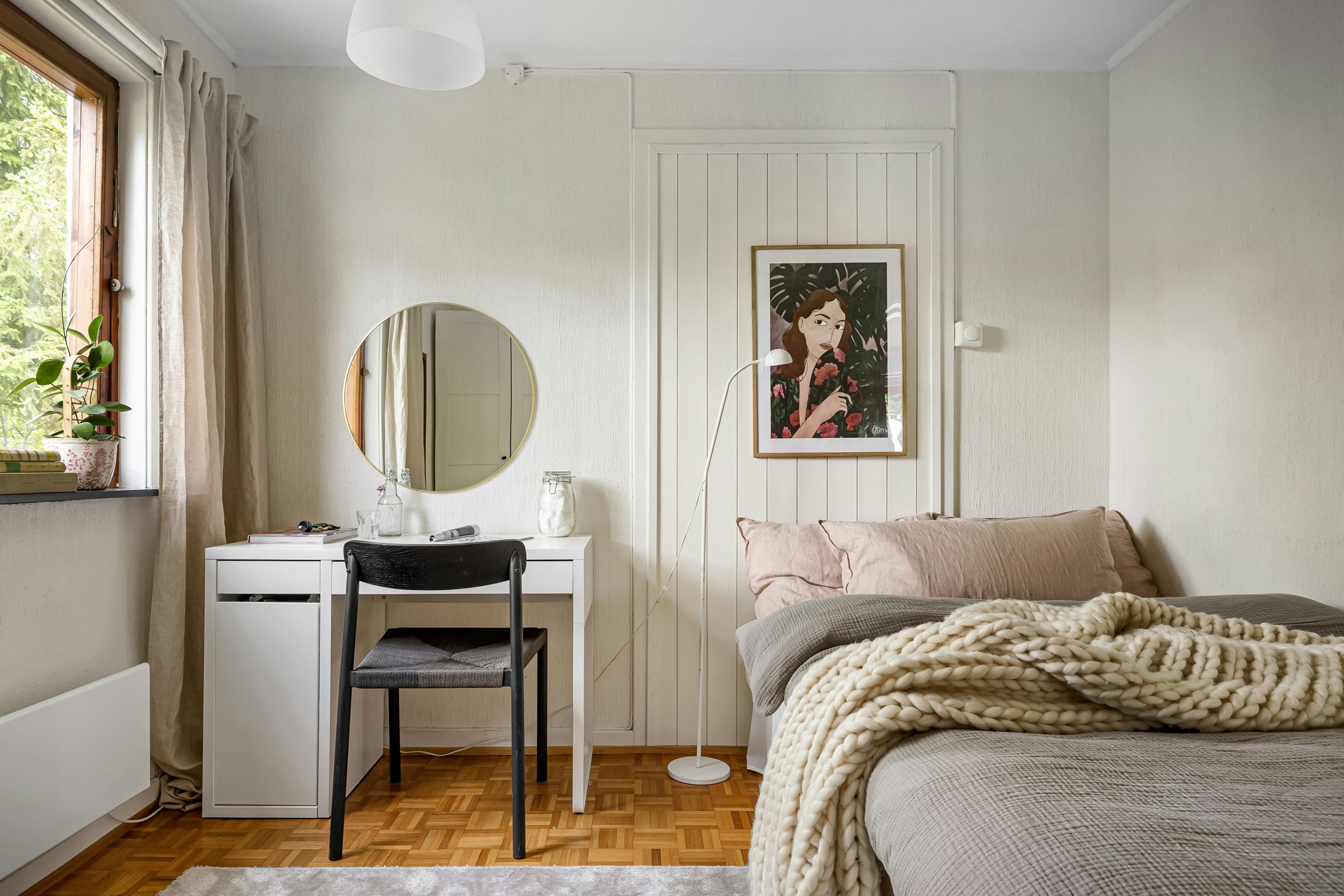 A bedroom with a bed, desk and mirror