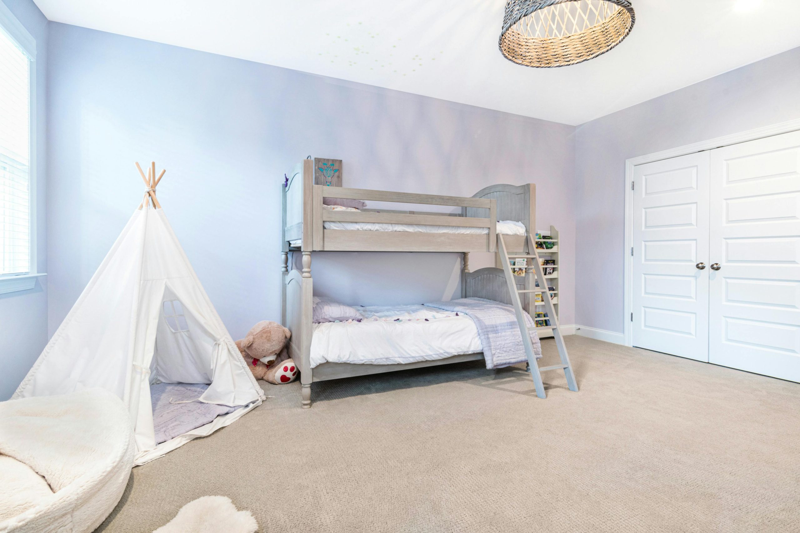A bright children's bedroom featuring a bunk bed, teepee tent, and playful decor.
