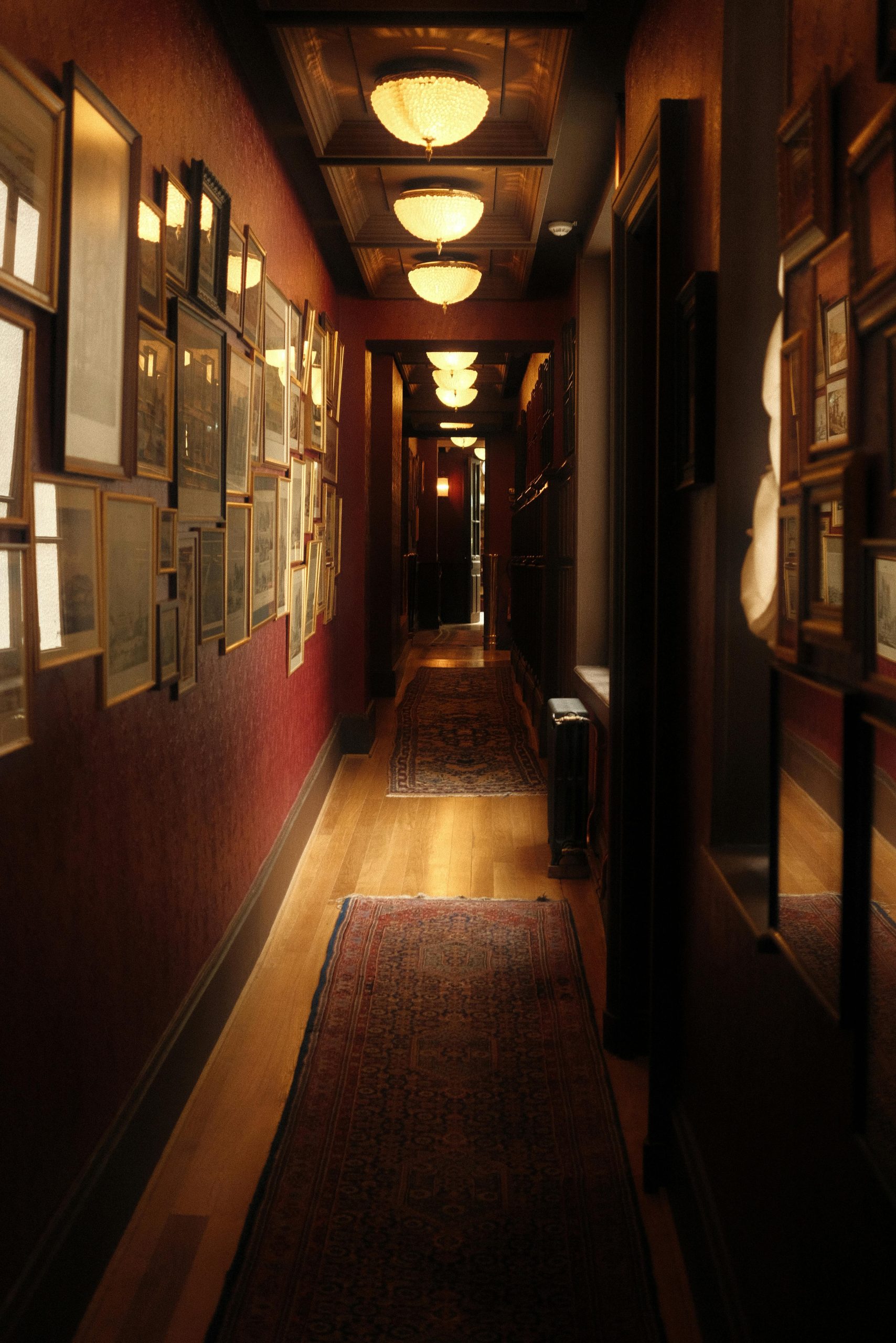 A narrow, art-decorated hallway with warm lighting and vintage decor.