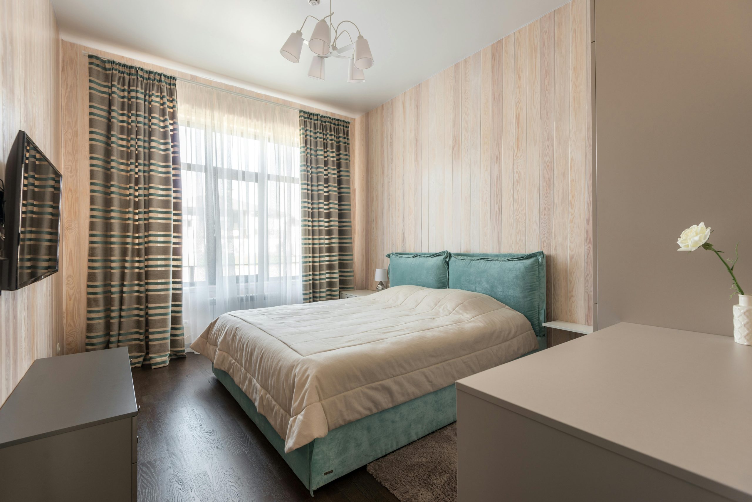 A serene minimalist bedroom with aqua bedding and striped curtains, featuring a cozy bed and natural light.