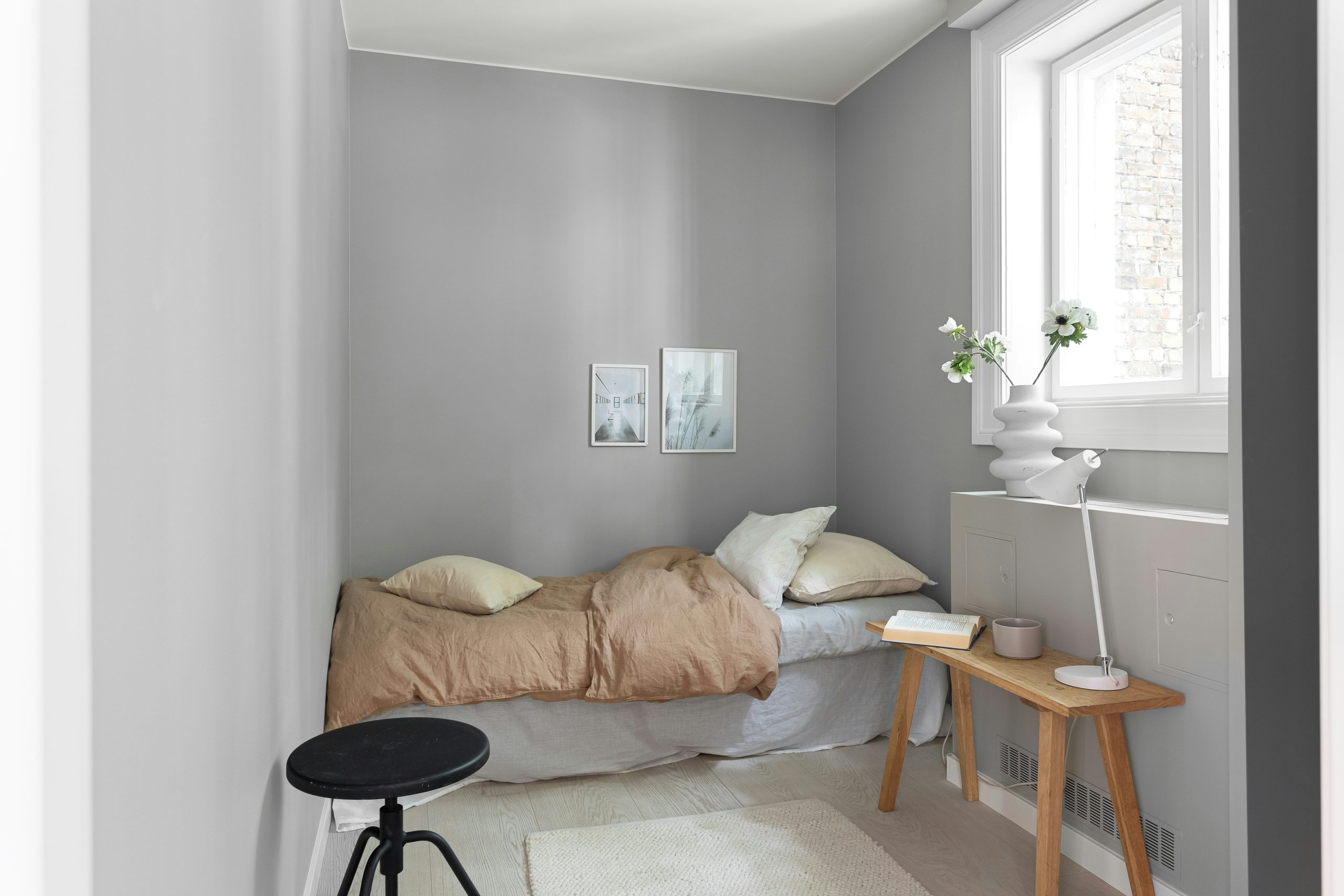 A small bedroom with a bed and a stool