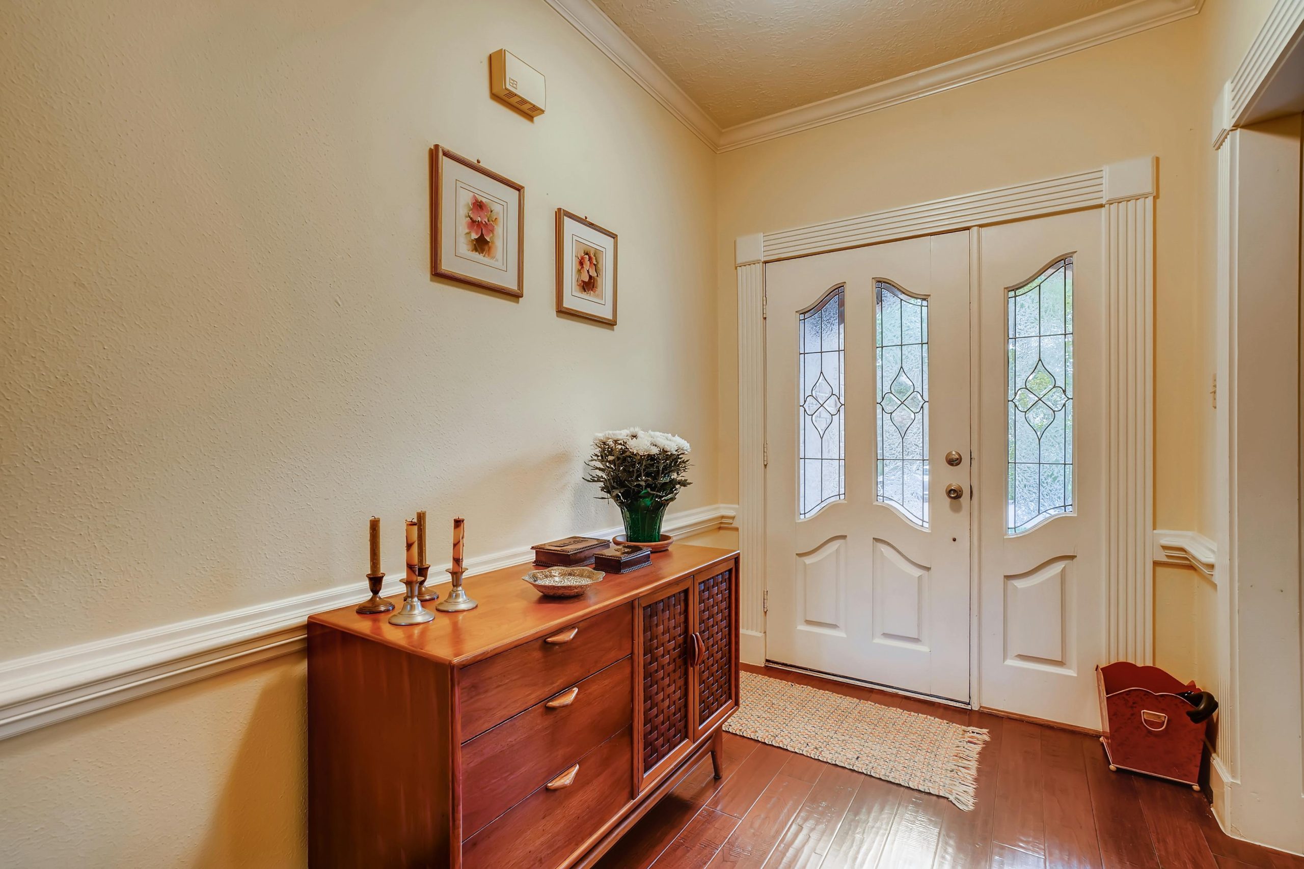 A stylish entryway featuring a wooden sideboard, decor, and a classic front door.