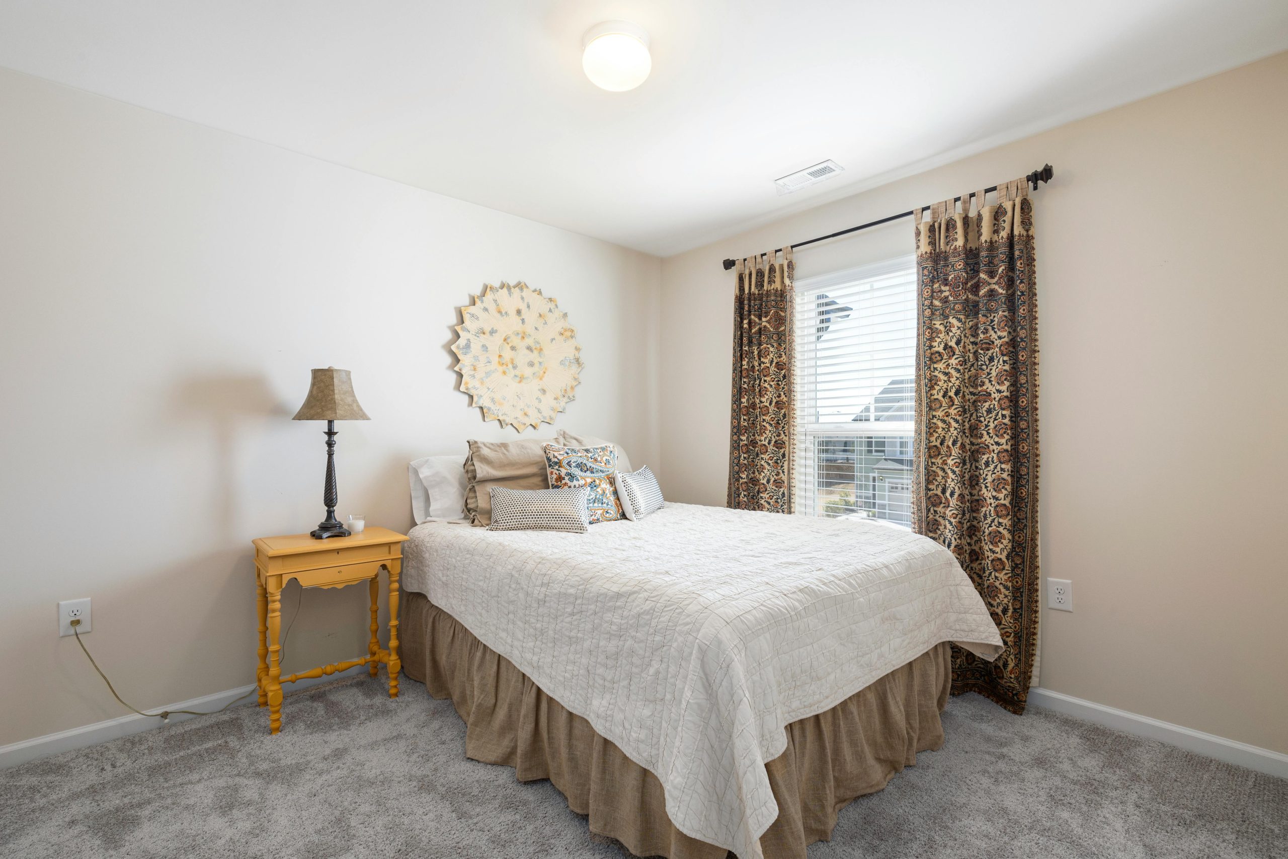A well-decorated bedroom with a comfortable bed, decorative pillows, and natural light streaming in.