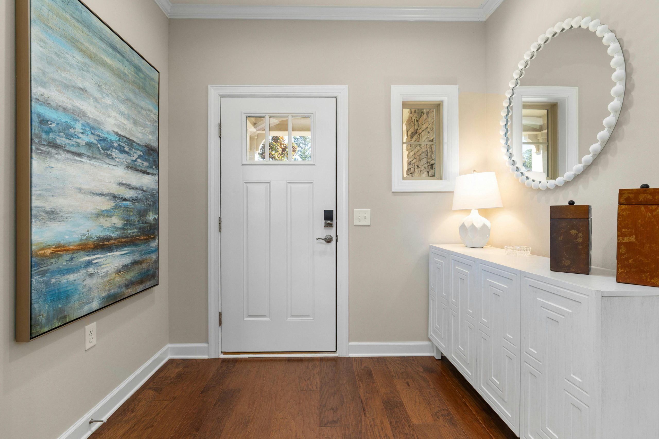Bright and modern entryway featuring abstract art, a white door, and elegant decor. Ideal for contemporary living spaces.
