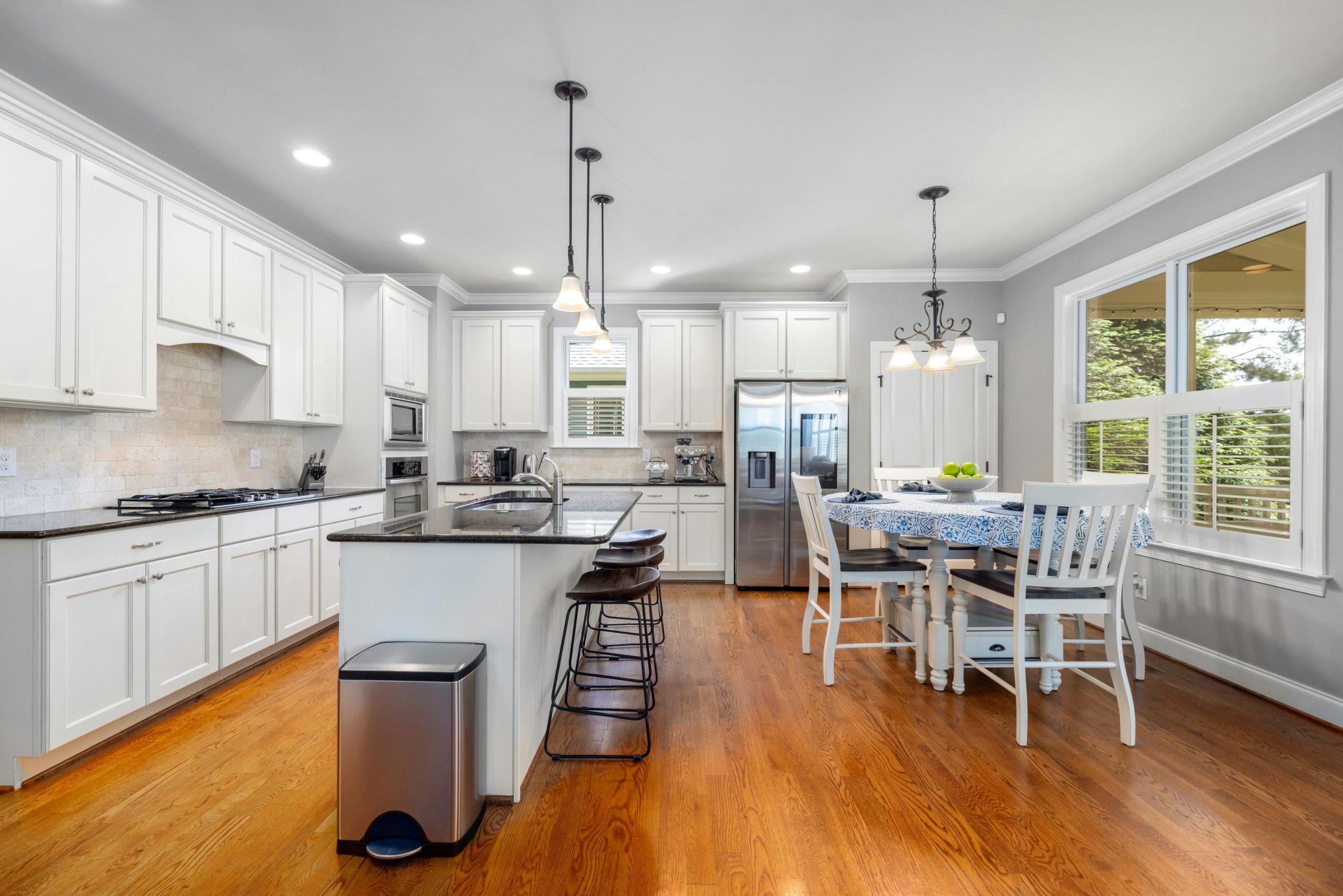 Bright and spacious modern kitchen with white cabinets and wooden flooring.