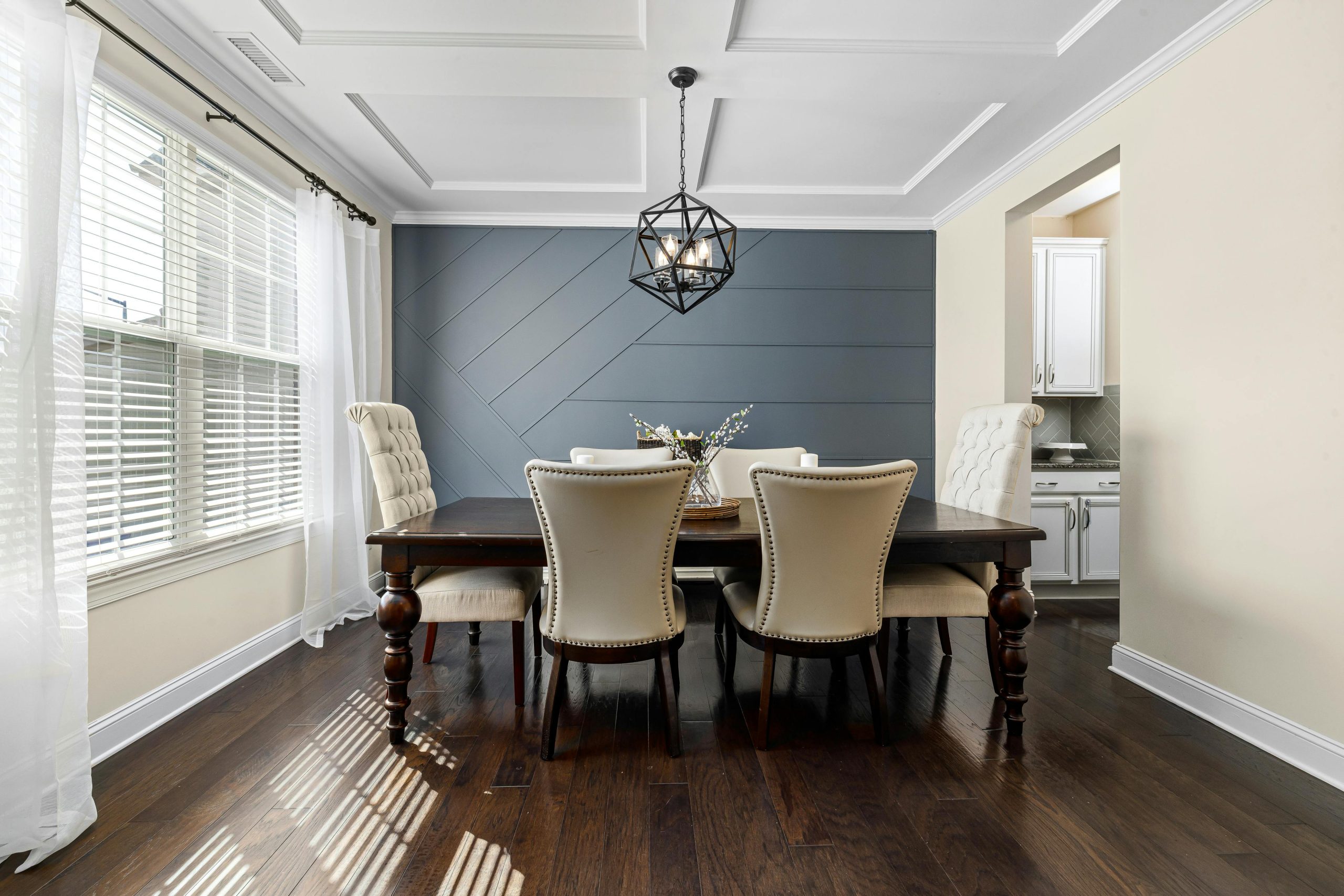 Bright dining room featuring a modern chandelier, elegant chairs, and a wooden table.