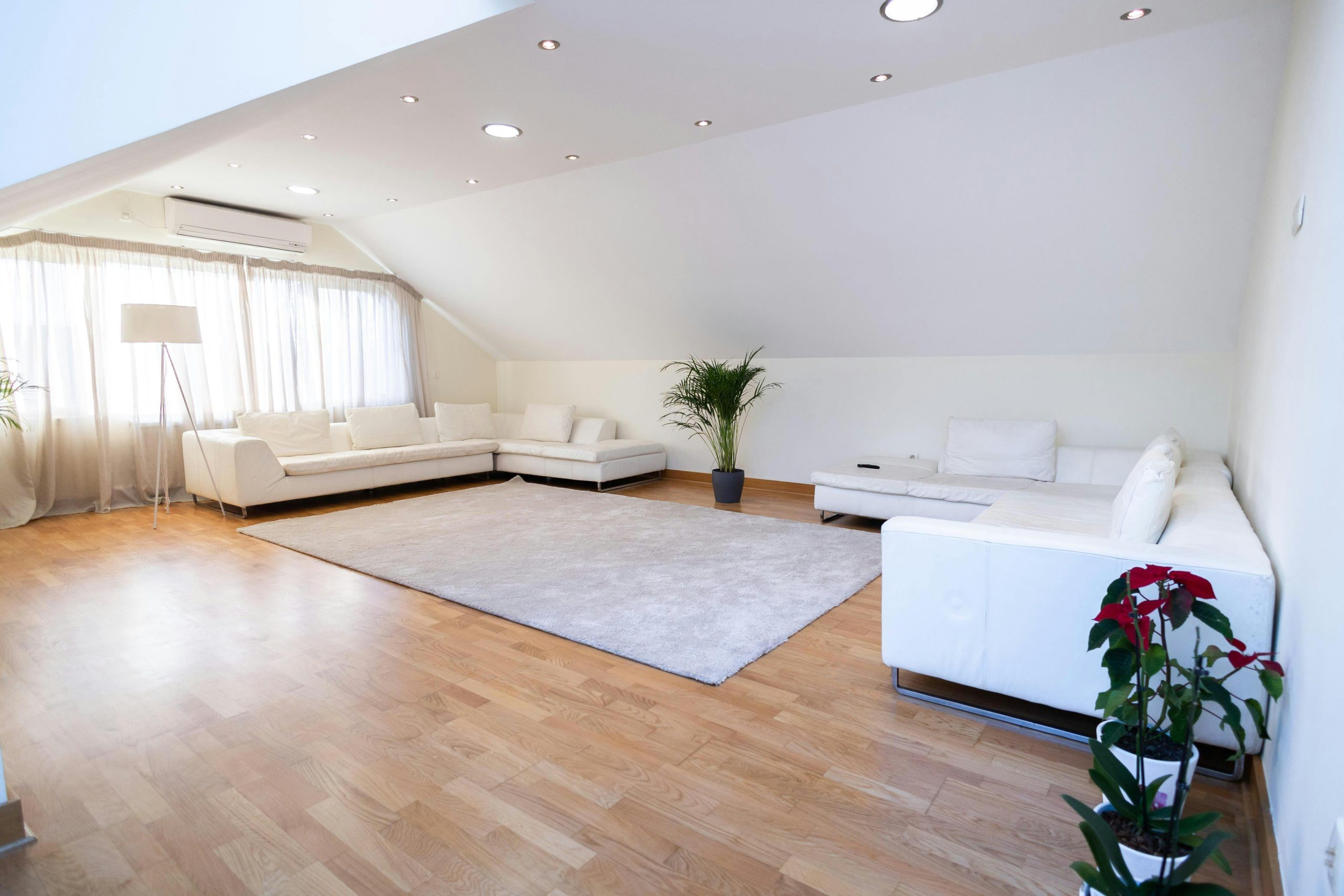Bright modern living room with white sofas and wooden floor, ideal for relaxation.