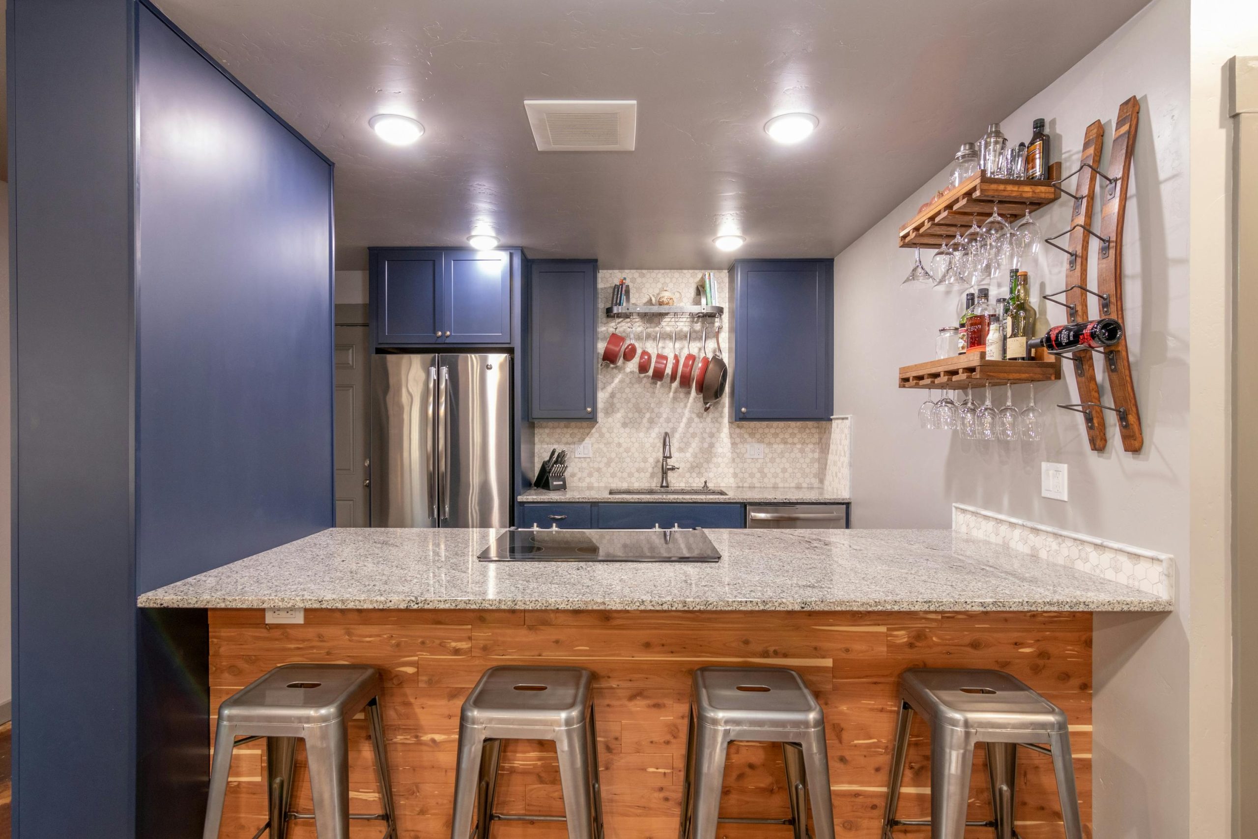 Contemporary kitchen featuring a granite island, bar stools, and blue cabinets for a stylish look.