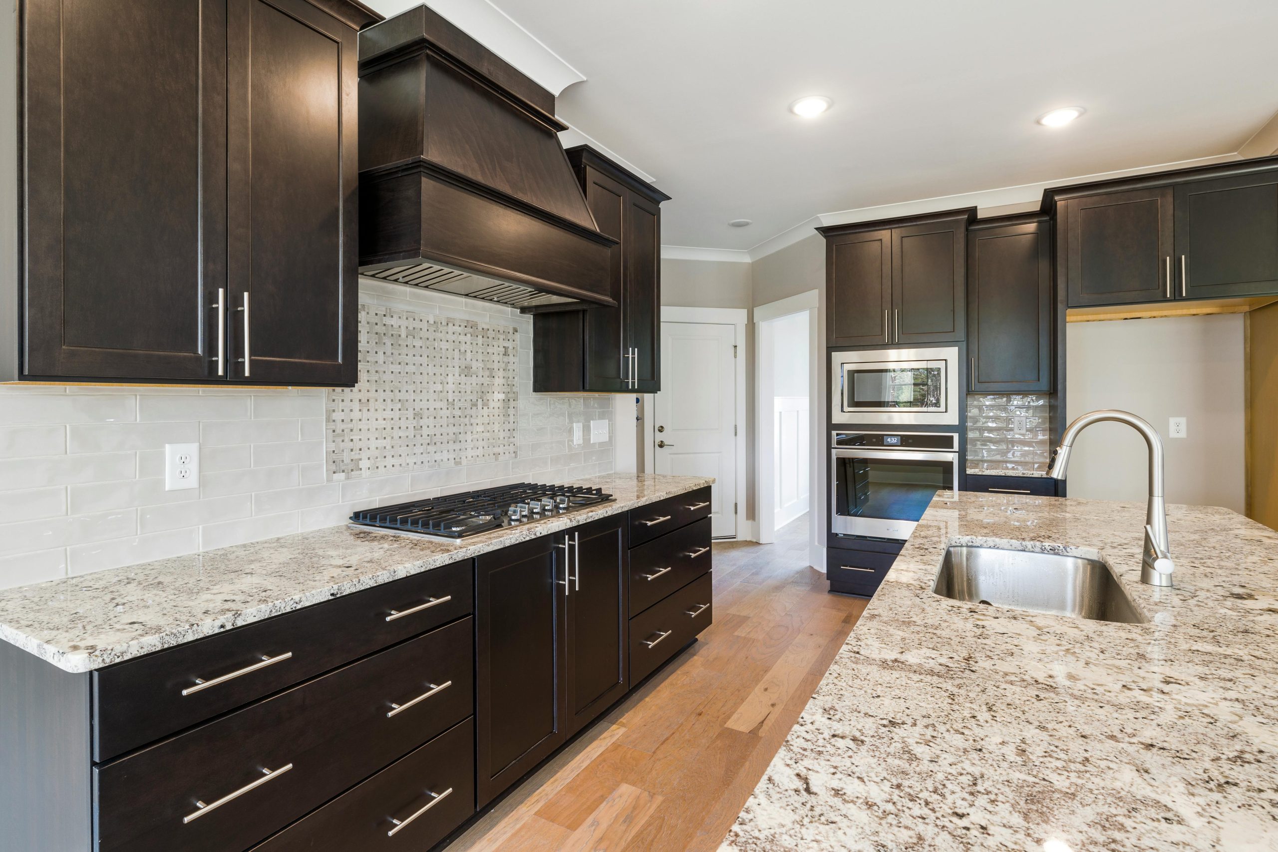 Contemporary kitchen featuring dark cabinetry, granite countertops, and stainless steel appliances.