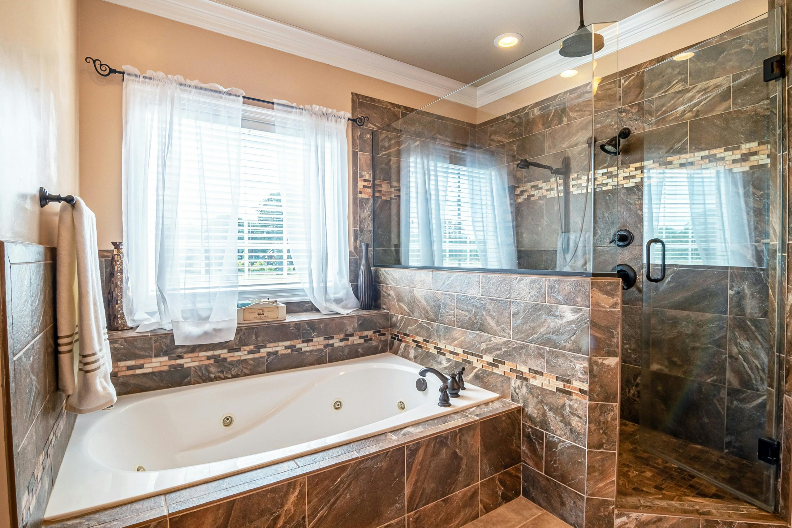 Elegant bathroom featuring a large bathtub and walk-in shower with marble tiles.