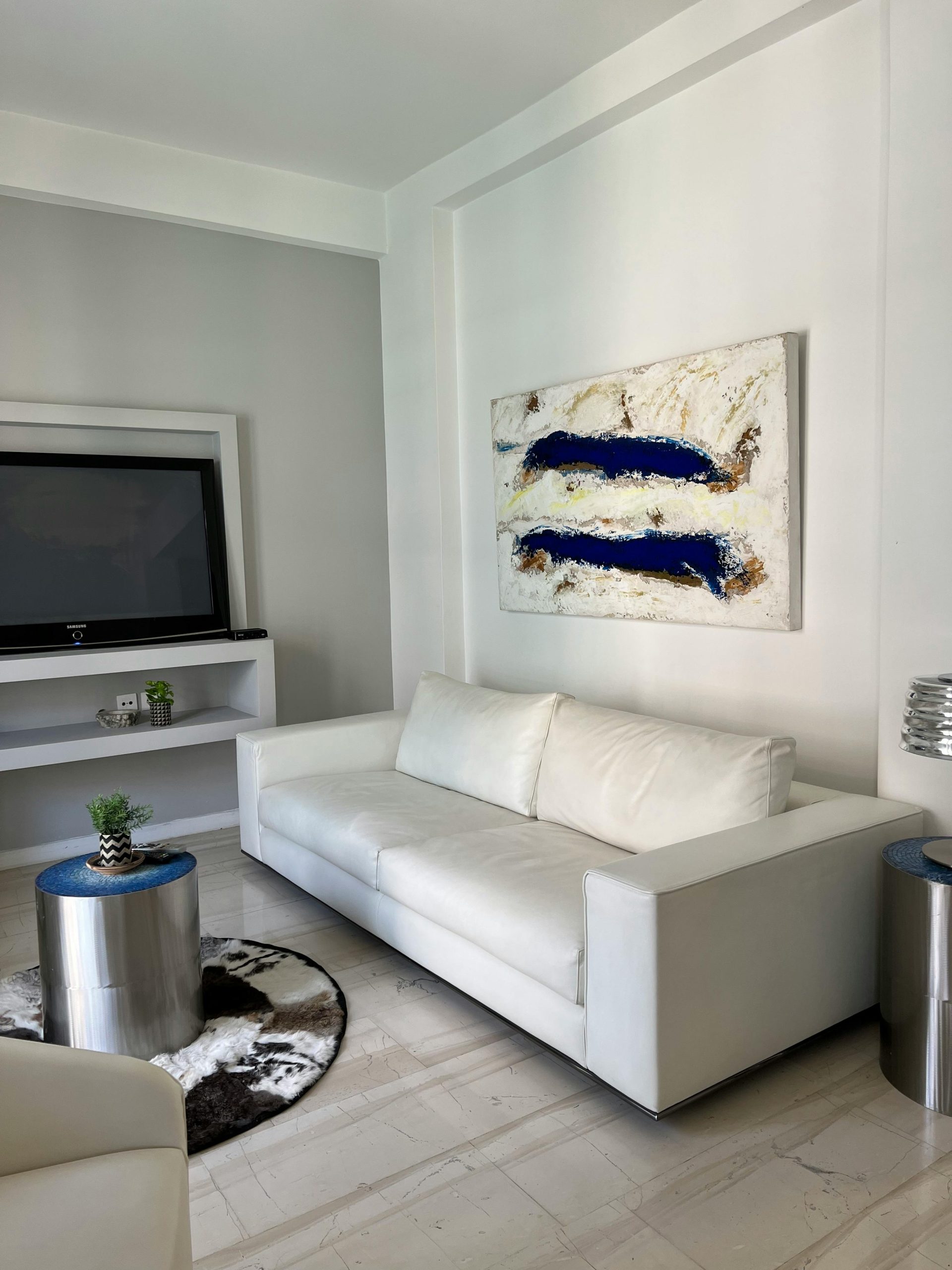 Elegant living room featuring a sleek white couch and abstract blue artwork.