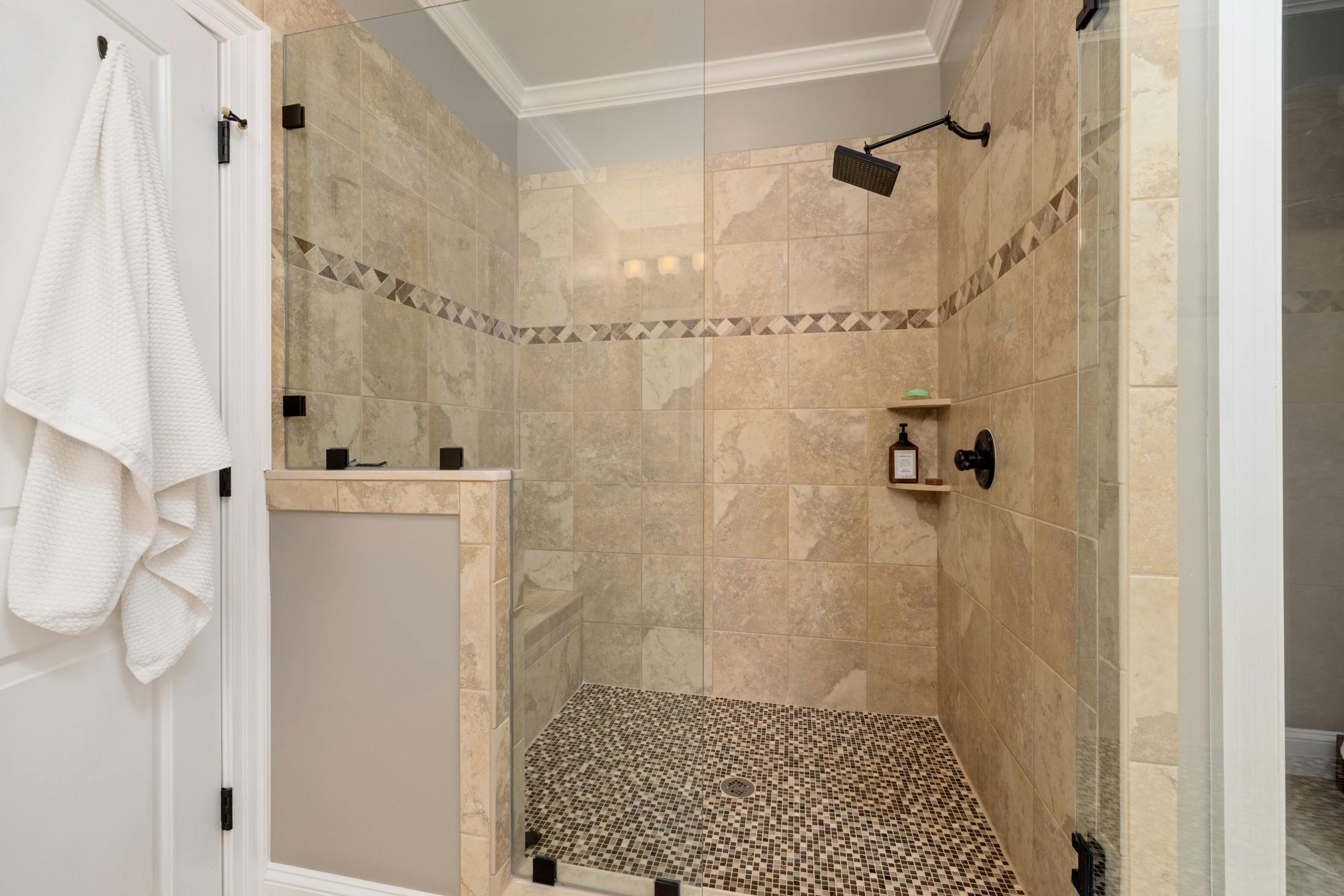Elegant tiled shower interior with glass door and modern fixtures.