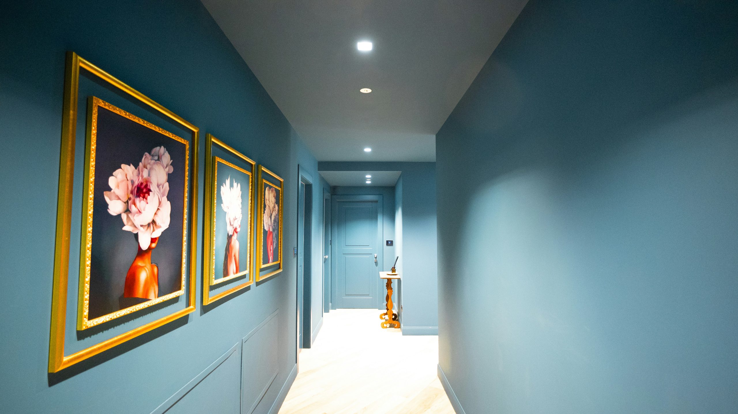 Hallway with blue walls and framed floral artwork.
