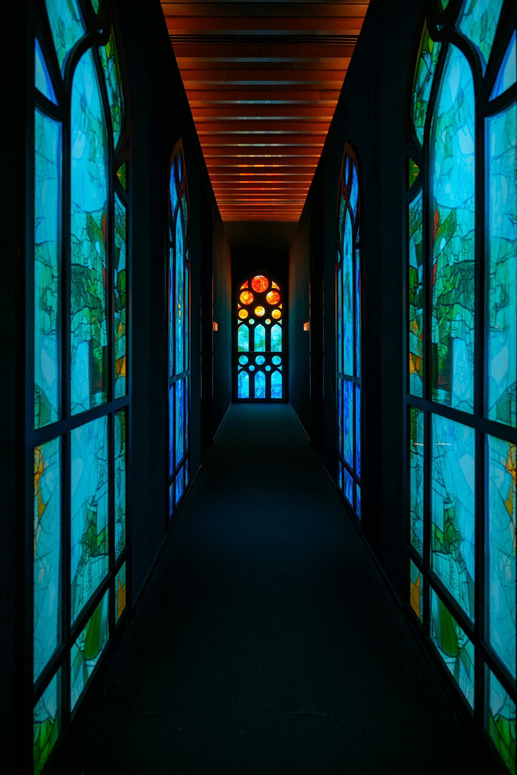 Hallway with colorful stained-glass windows and a door.