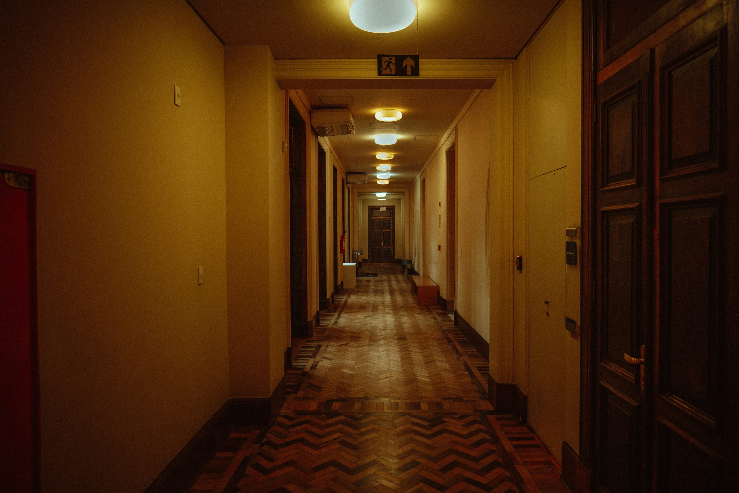 Long, dimly lit hotel hallway with doors on the sides.