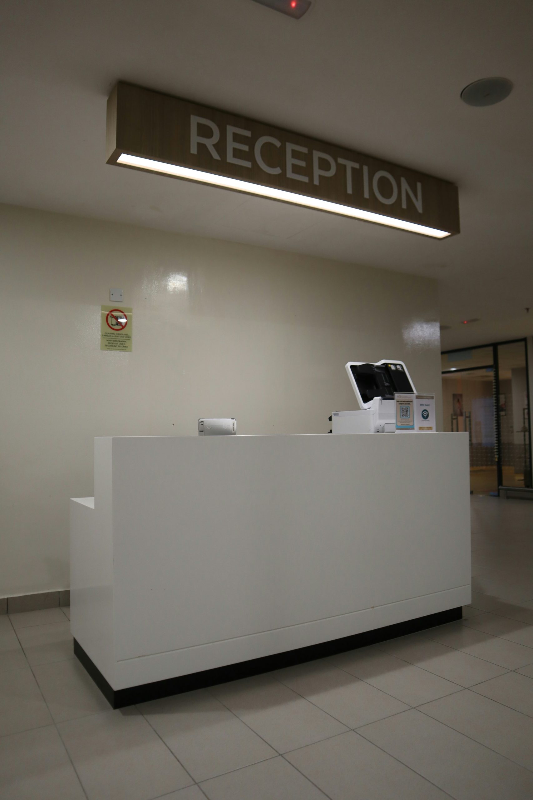Modern reception desk with sign overhead.