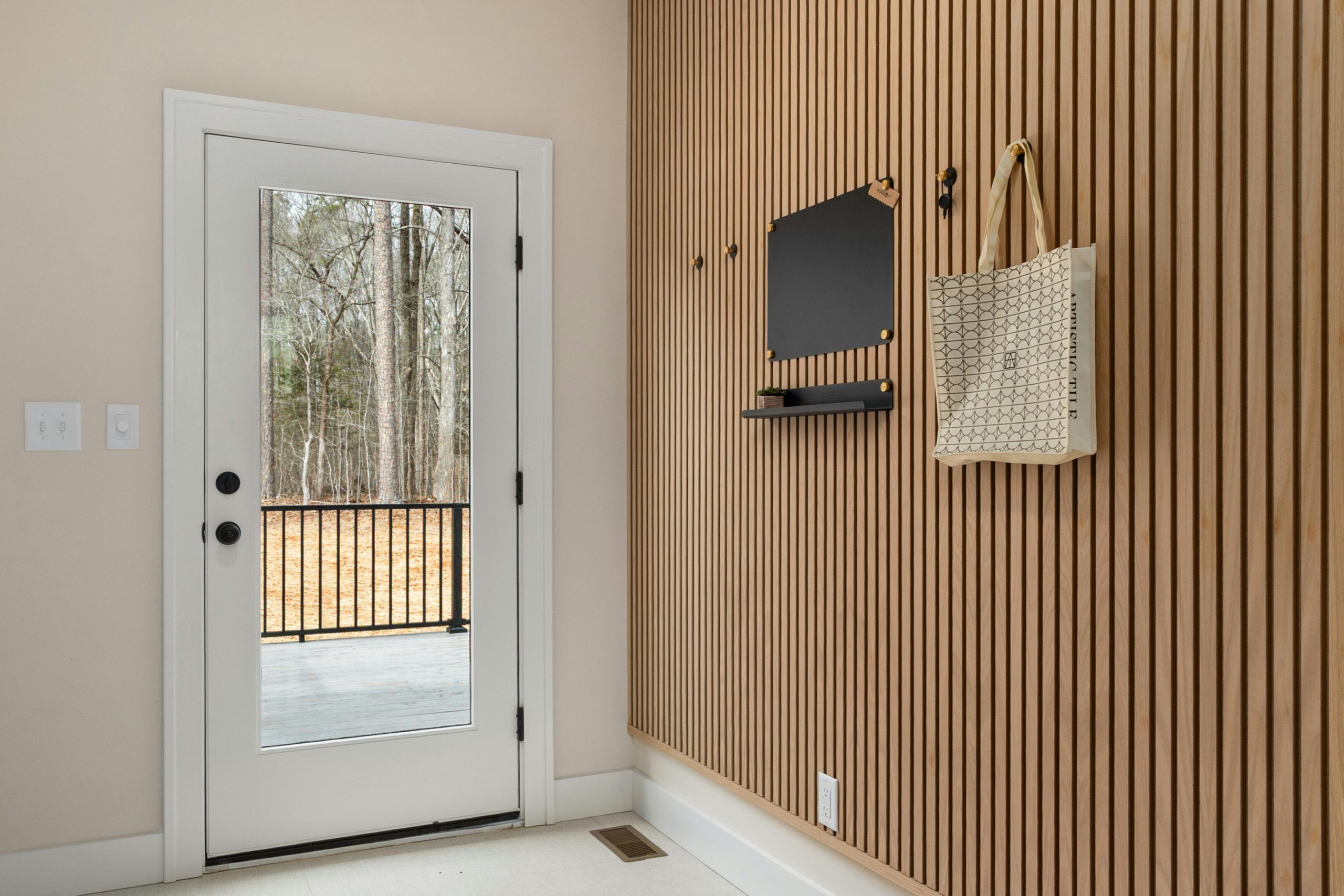 Sleek entryway featuring wood paneling, glass door, and stylish decor. Perfect for contemporary homes.