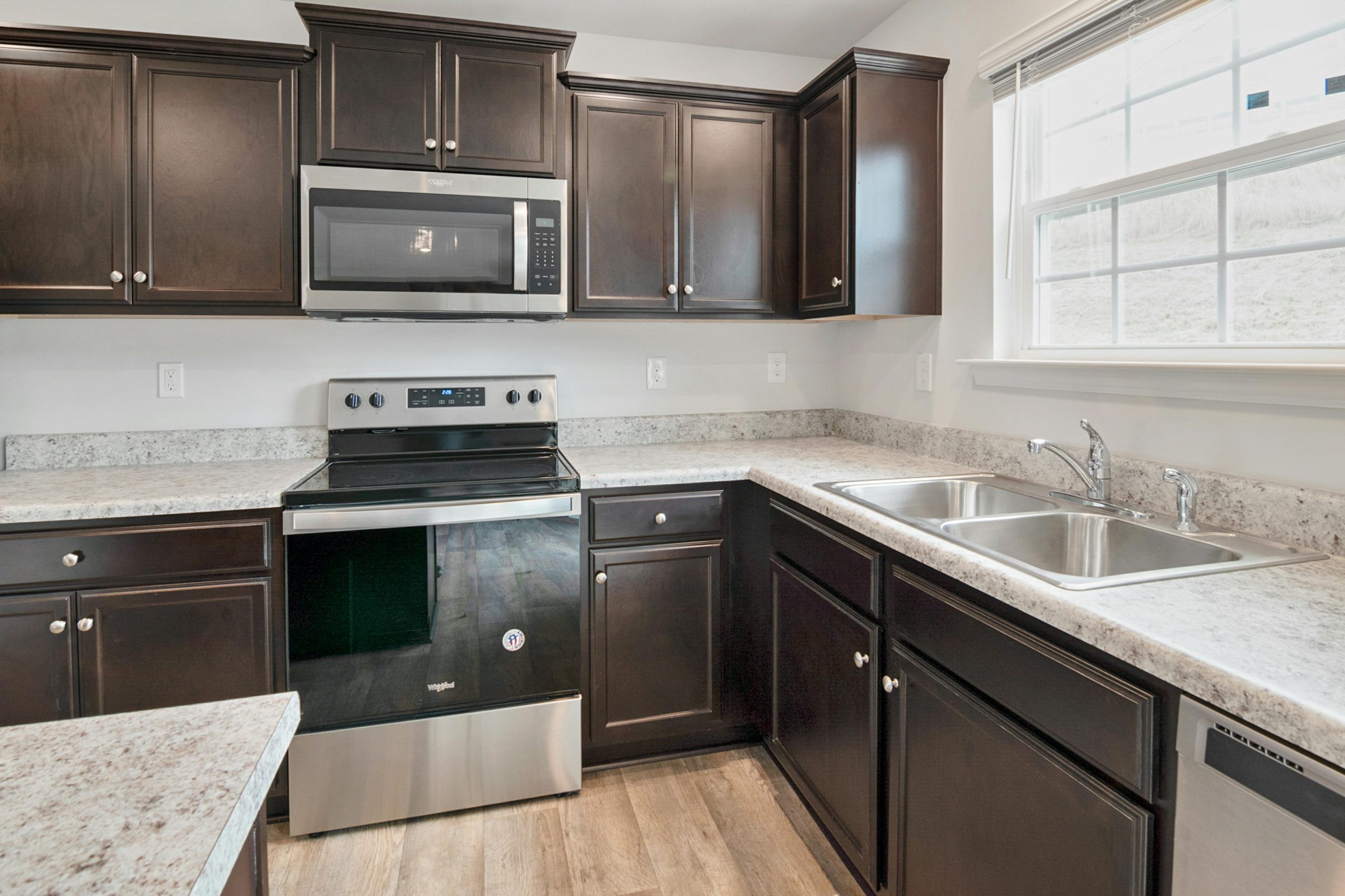 Sleek kitchen interior featuring dark wood cabinets, stainless steel appliances, and ample counter space.