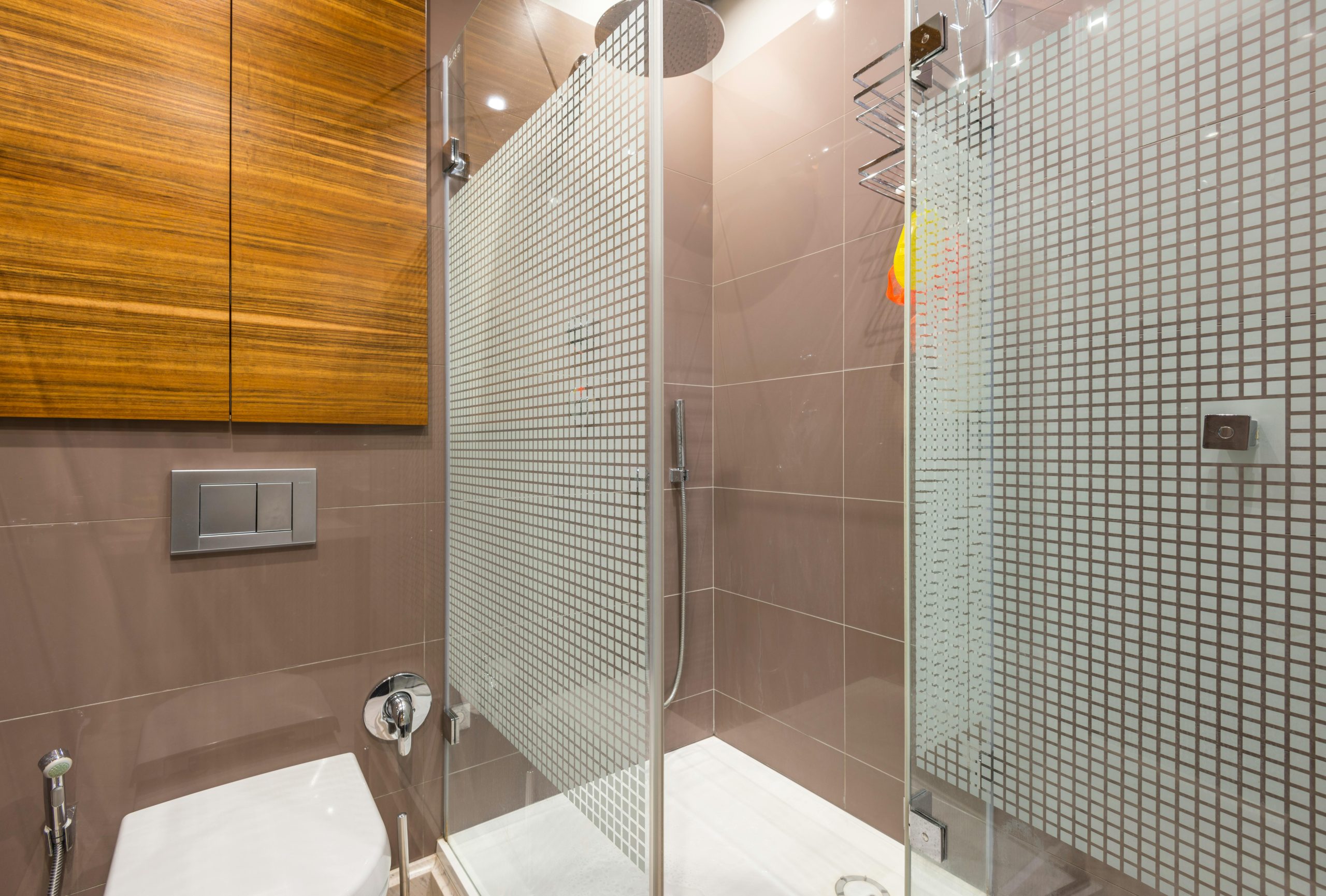 Sleek modern bathroom featuring a glass shower and wooden cabinetry.