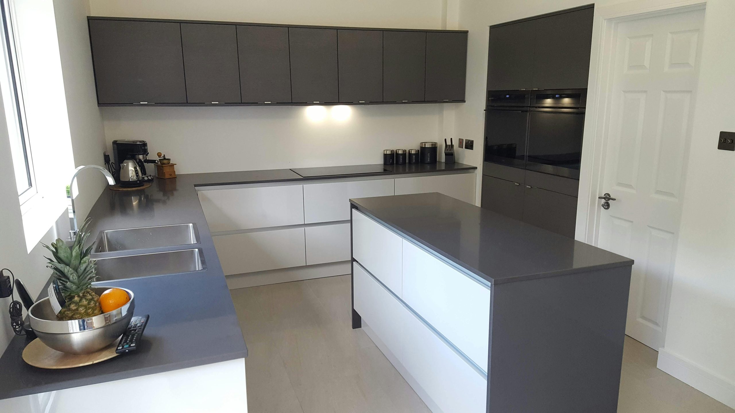 Sleek modern kitchen with dark cabinets, island, and elegant lighting.