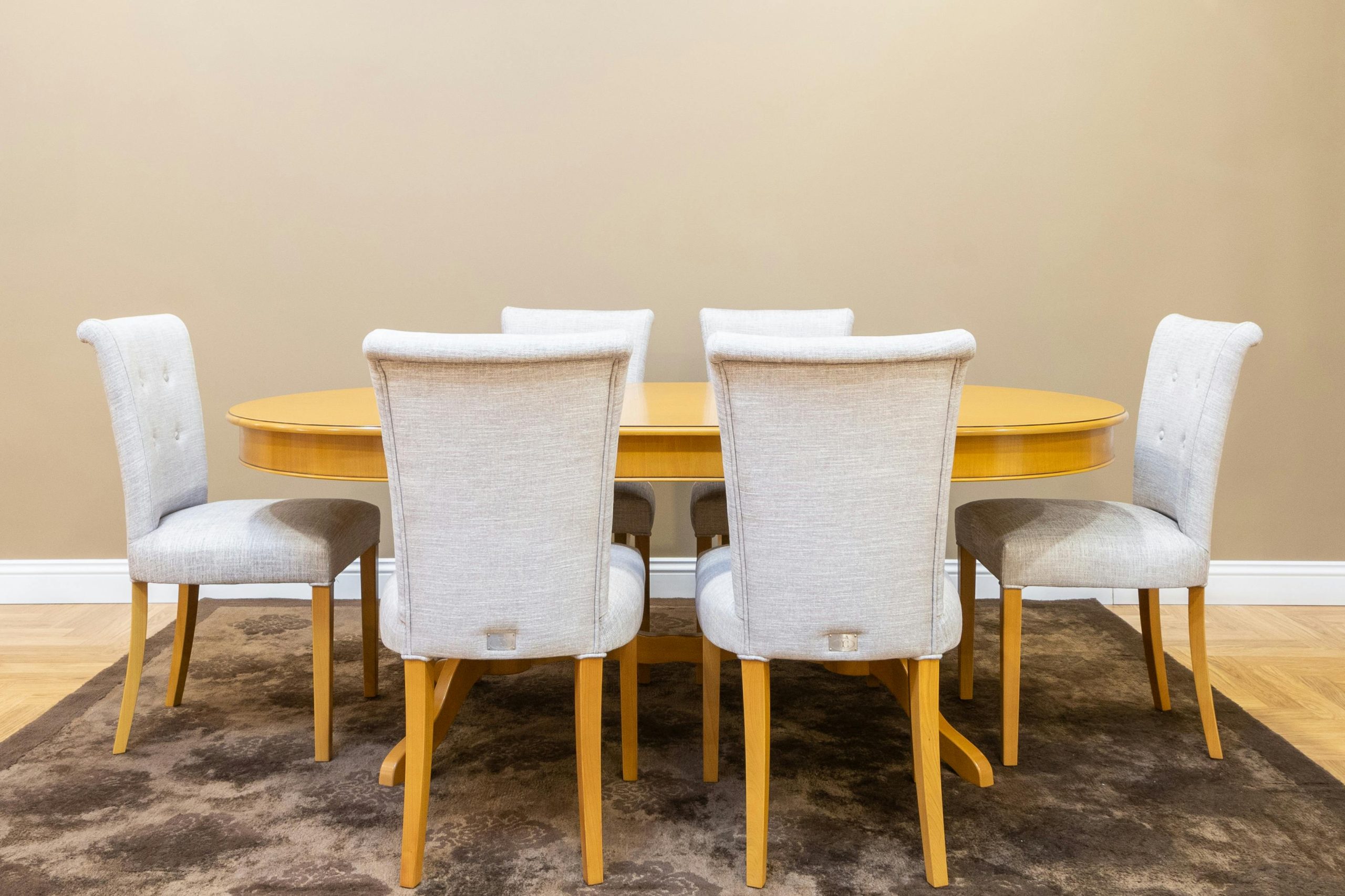 Sophisticated dining area showcasing a wooden table with beige upholstered chairs on a carpet.
