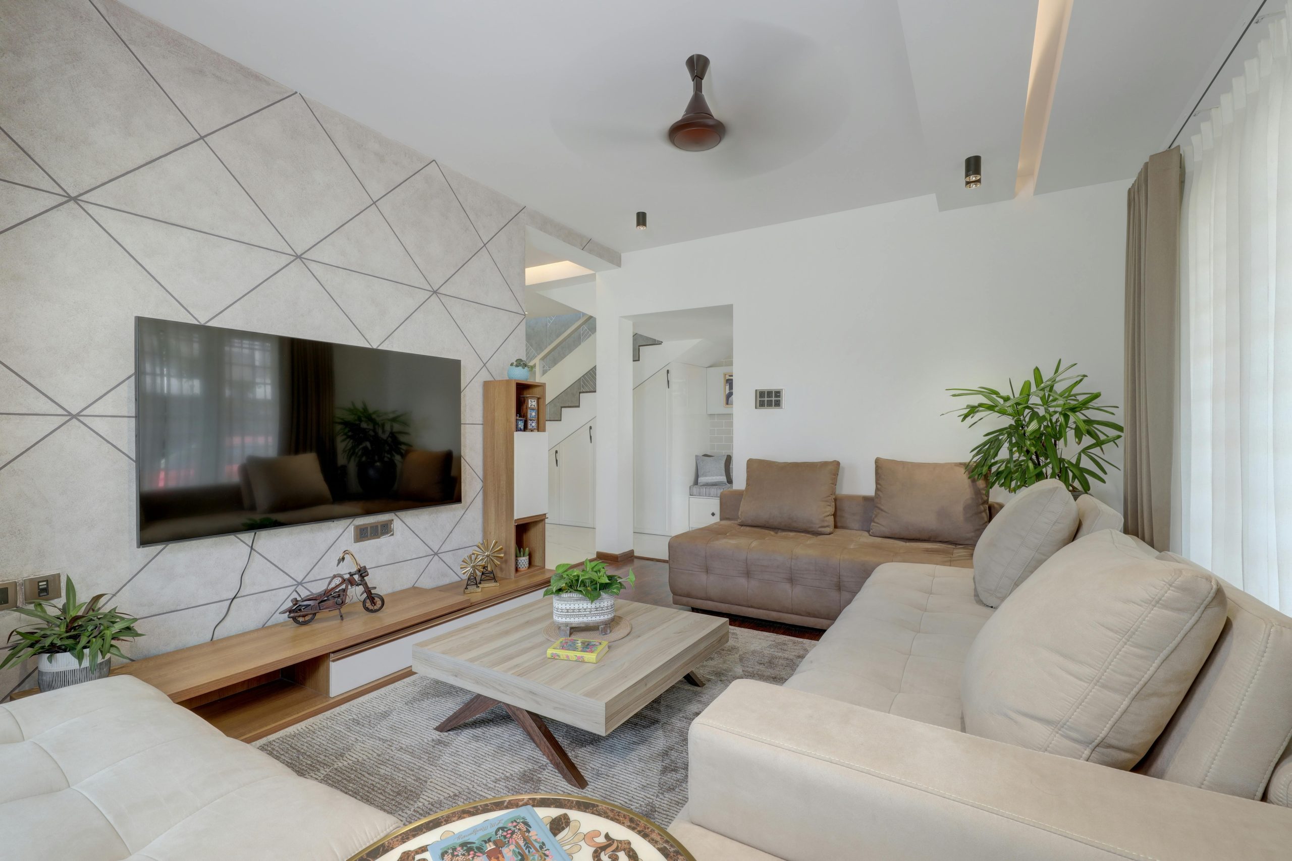 Spacious and elegant living room with neutral decor and geometric wall designs in Coimbatore, India.