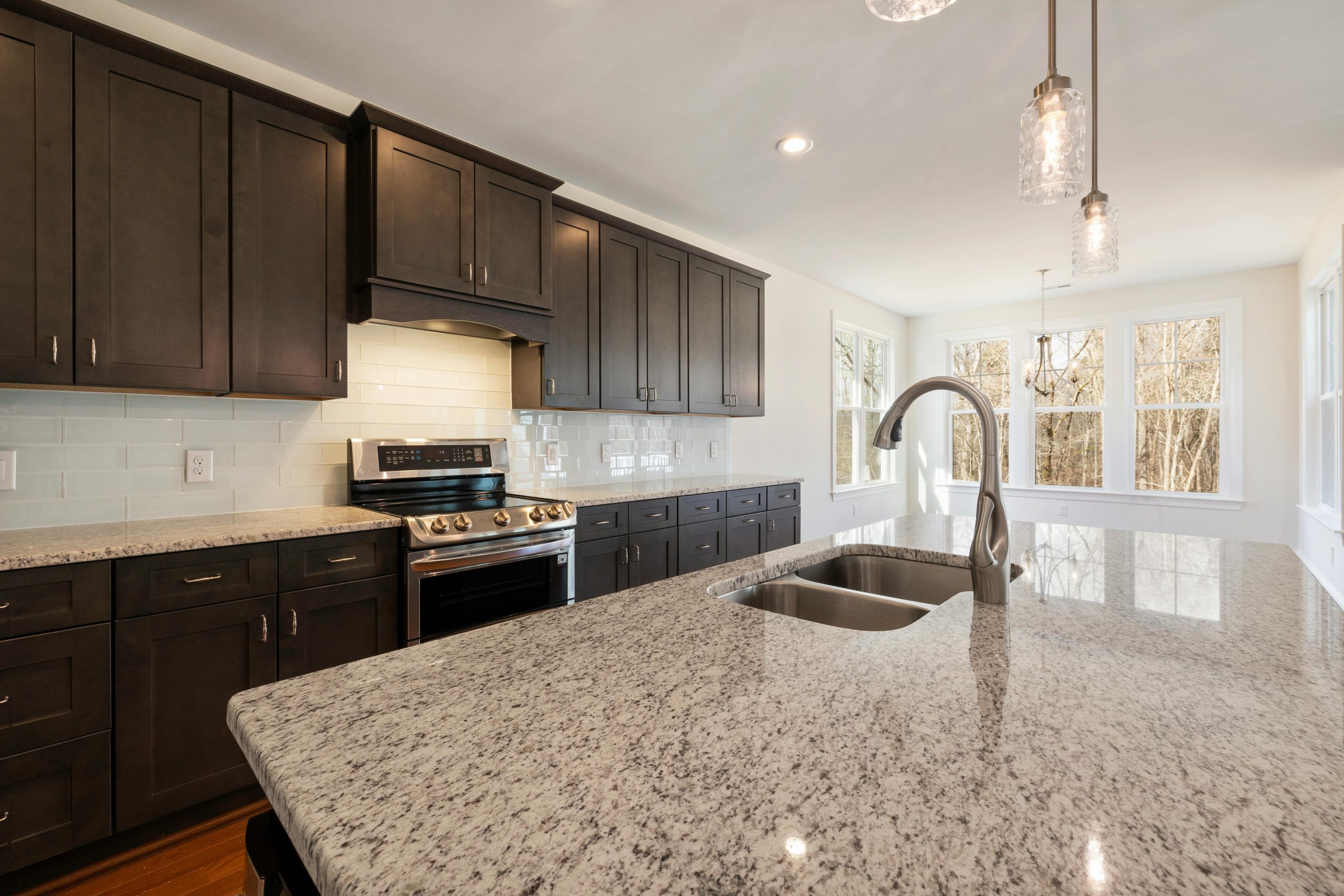 Spacious kitchen with granite island, dark wood cabinets, and large windows.