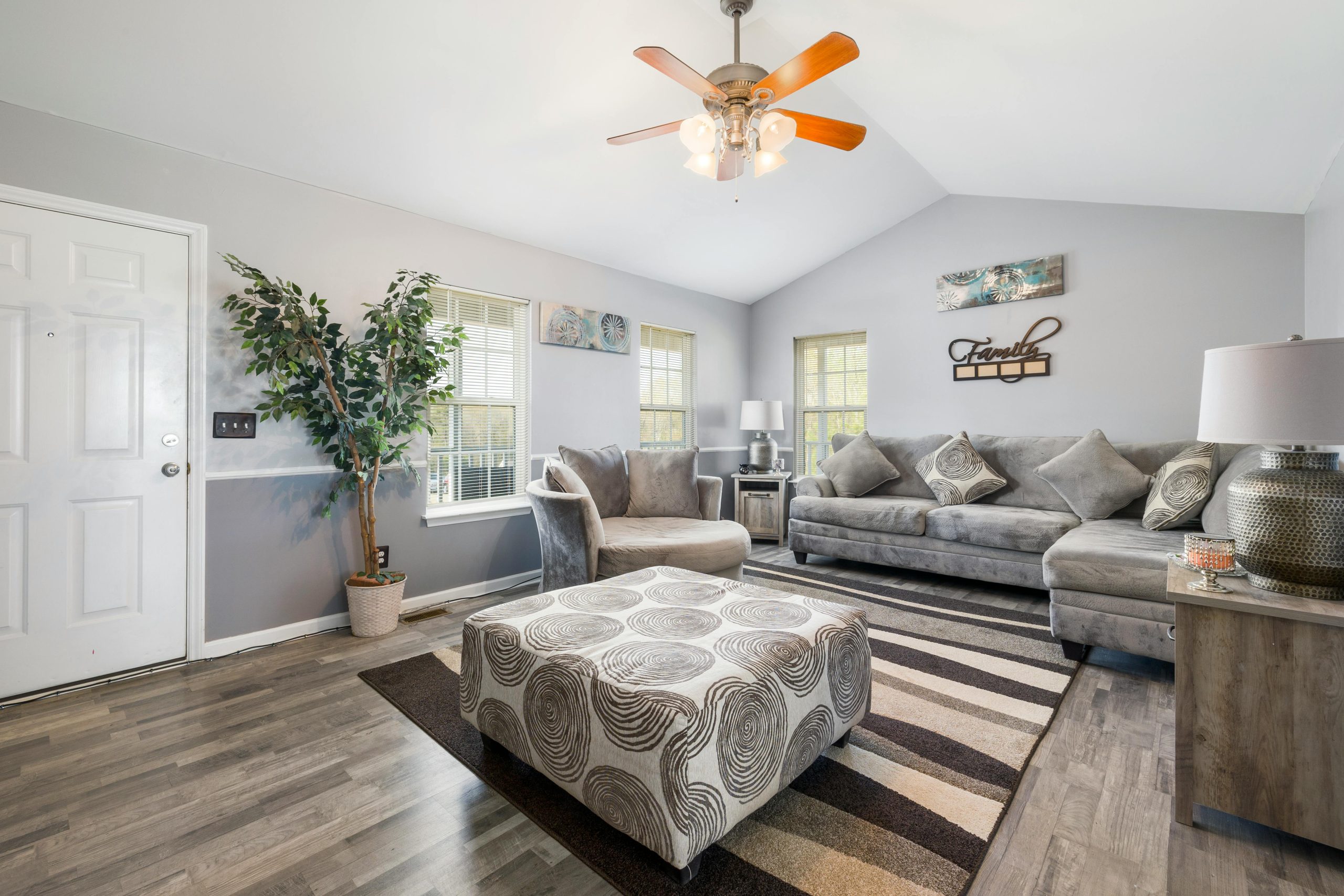 Spacious living room featuring gray sofas, stylish decor, and ample natural light.