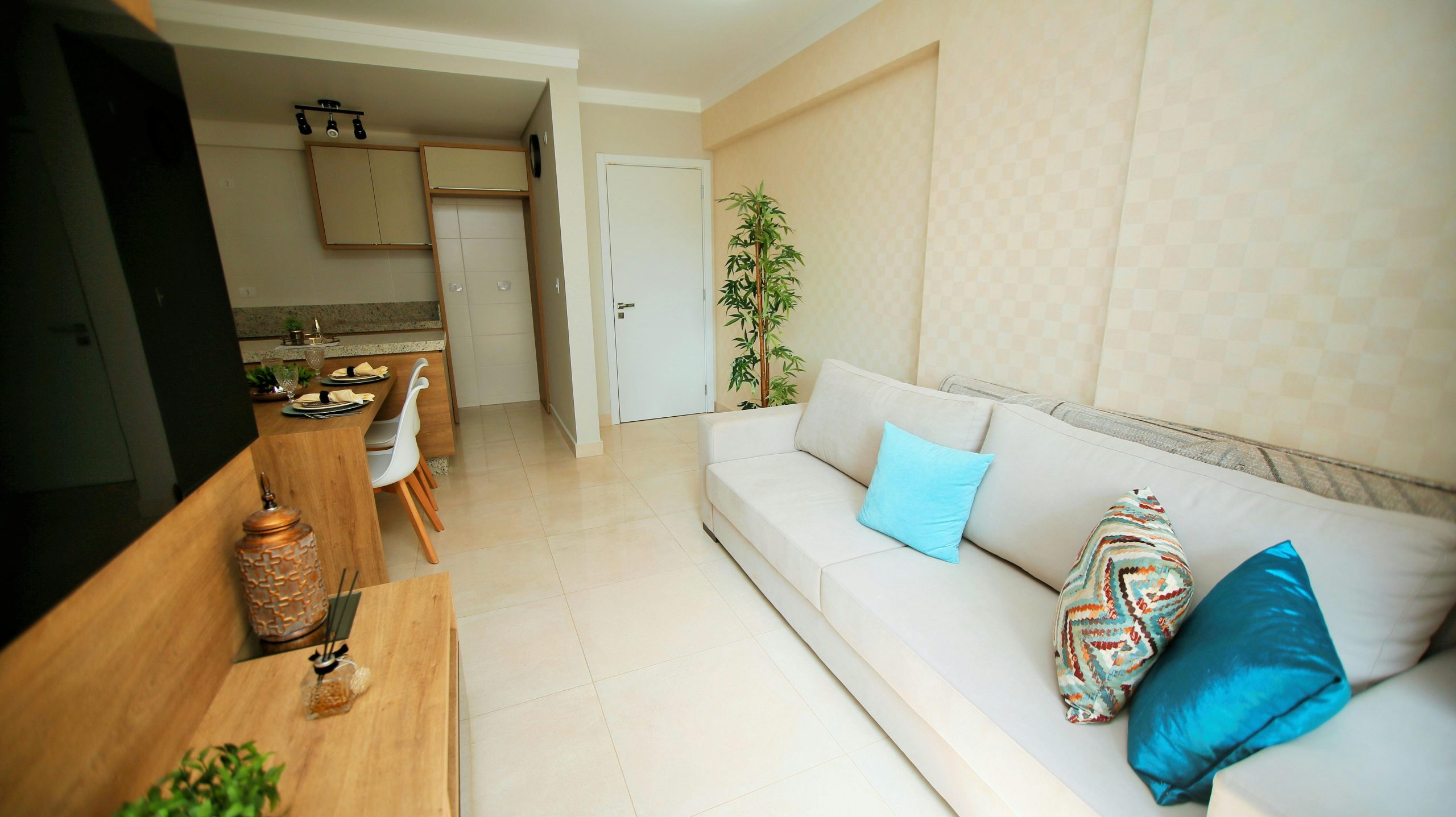 Spacious modern living room with a white couch, blue pillows, and a compact dining area.