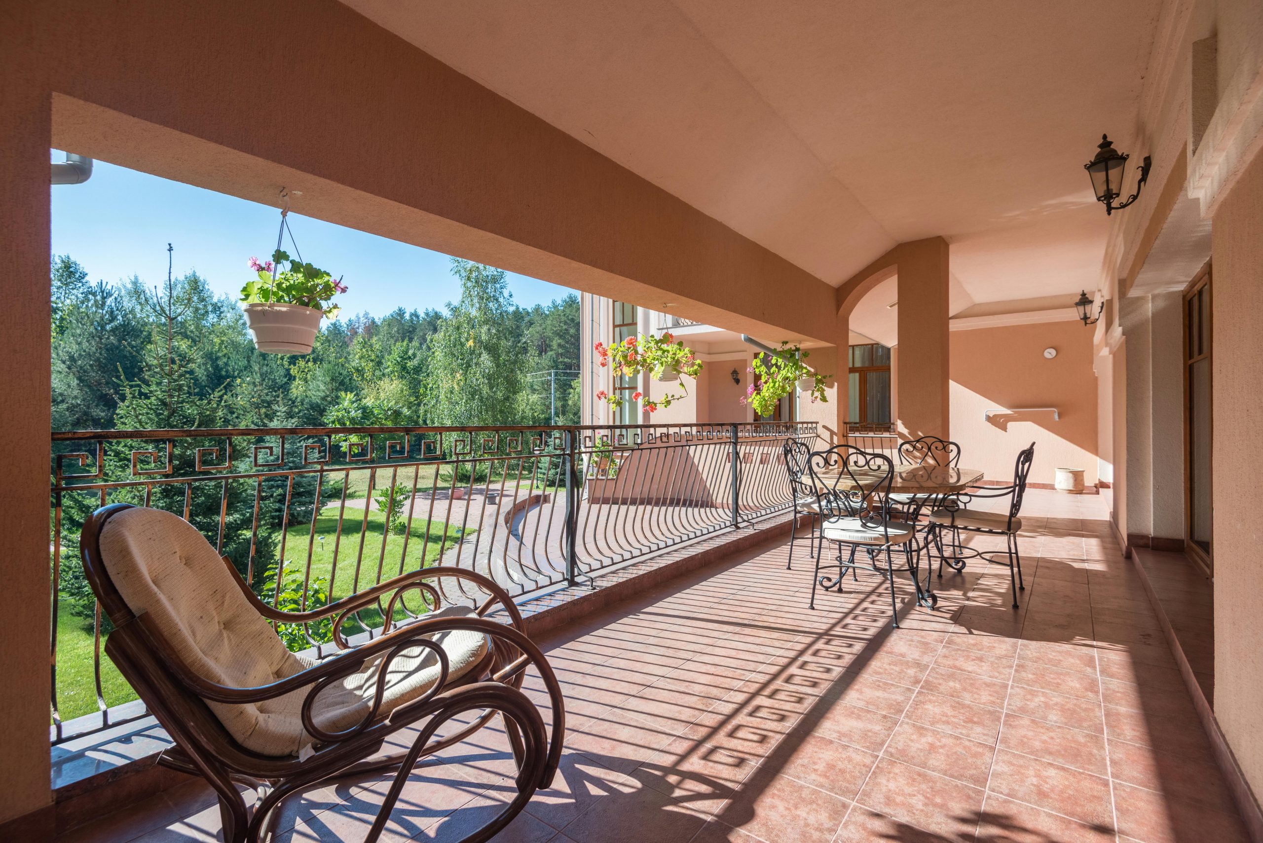 Spacious outdoor terrace with elegant metal furniture and lush garden view.