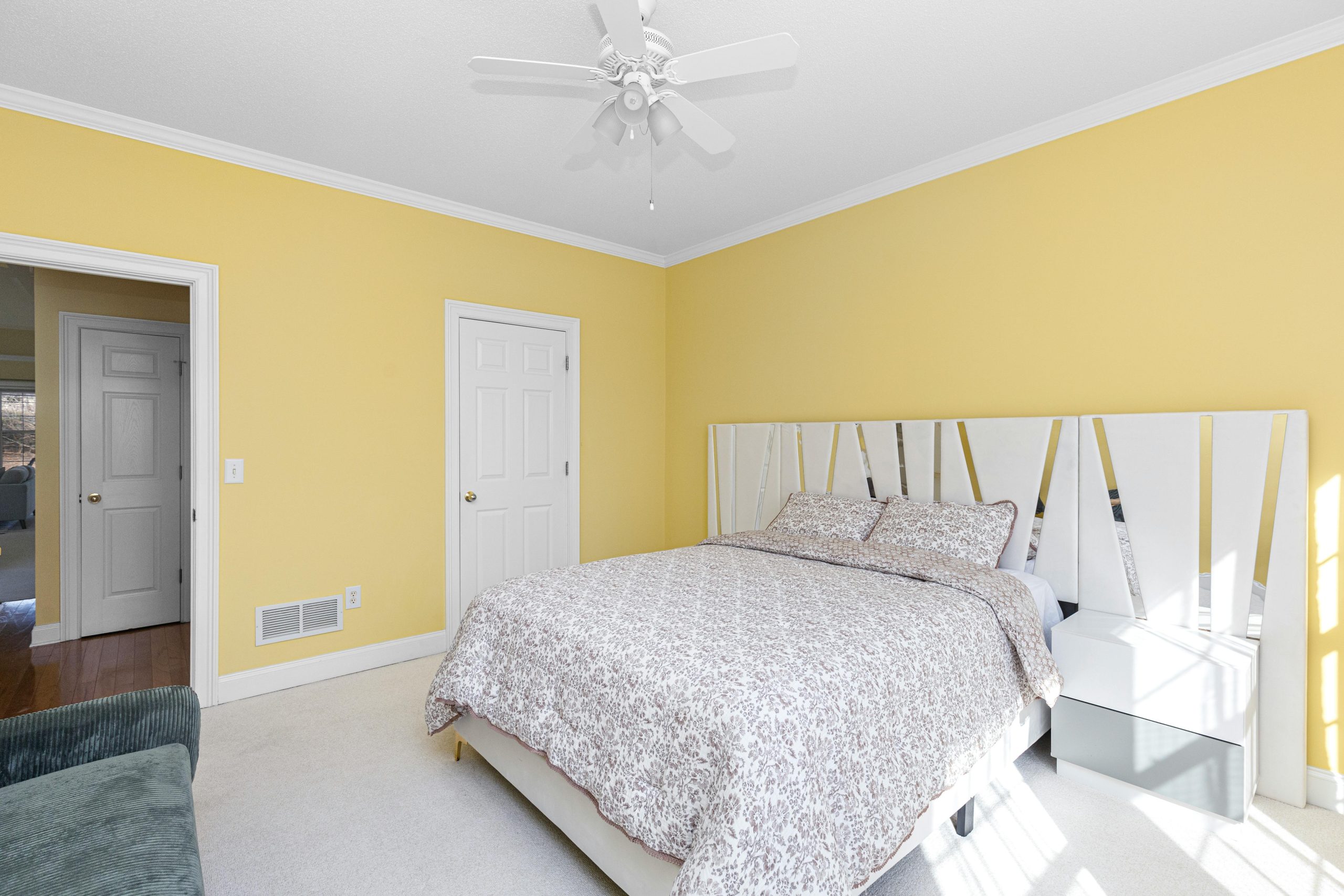 Spacious yellow bedroom with stylish white furniture and natural light.