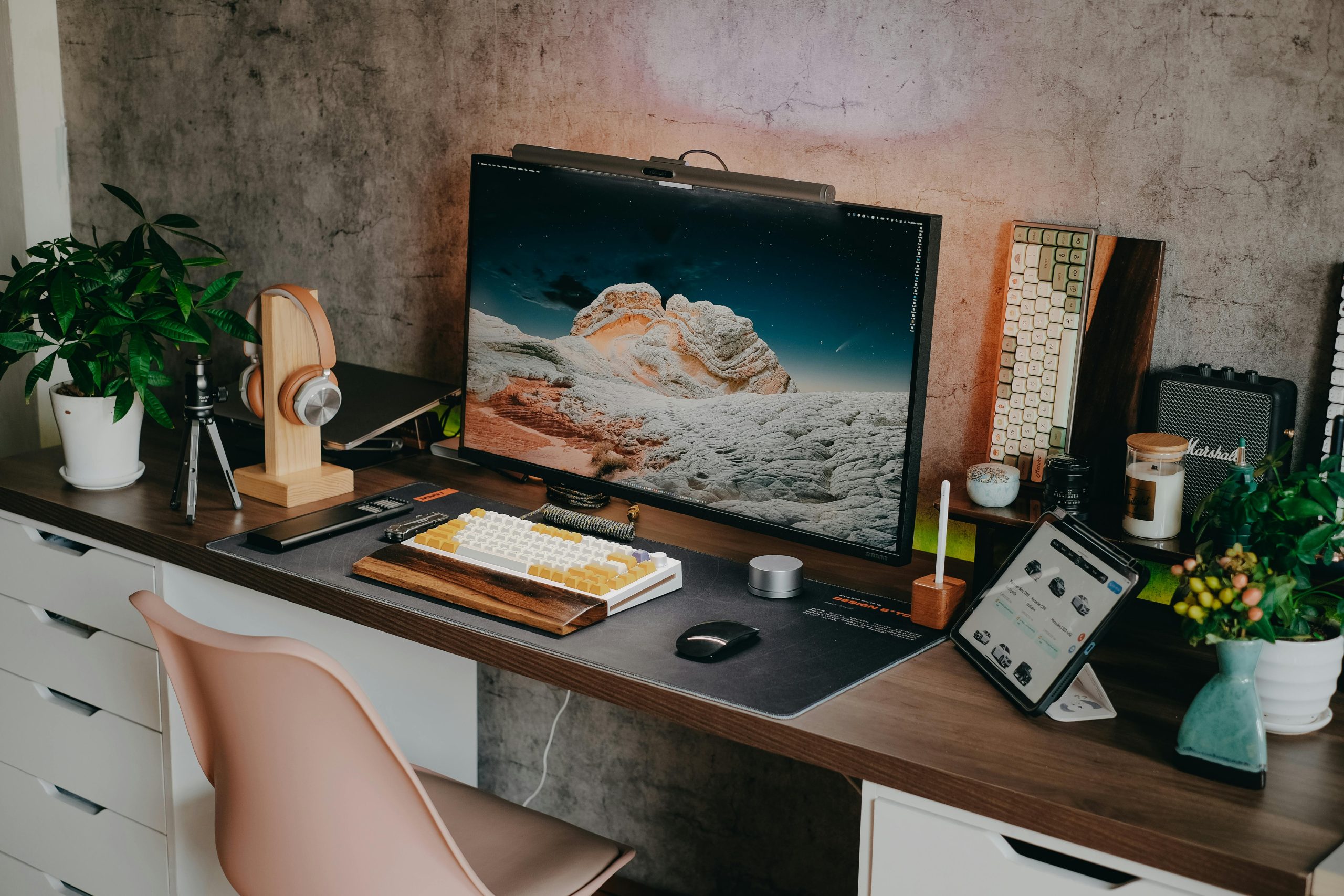 Stylish desk setup featuring a mechanical keyboard, monitor, plants, and tech gadgets.