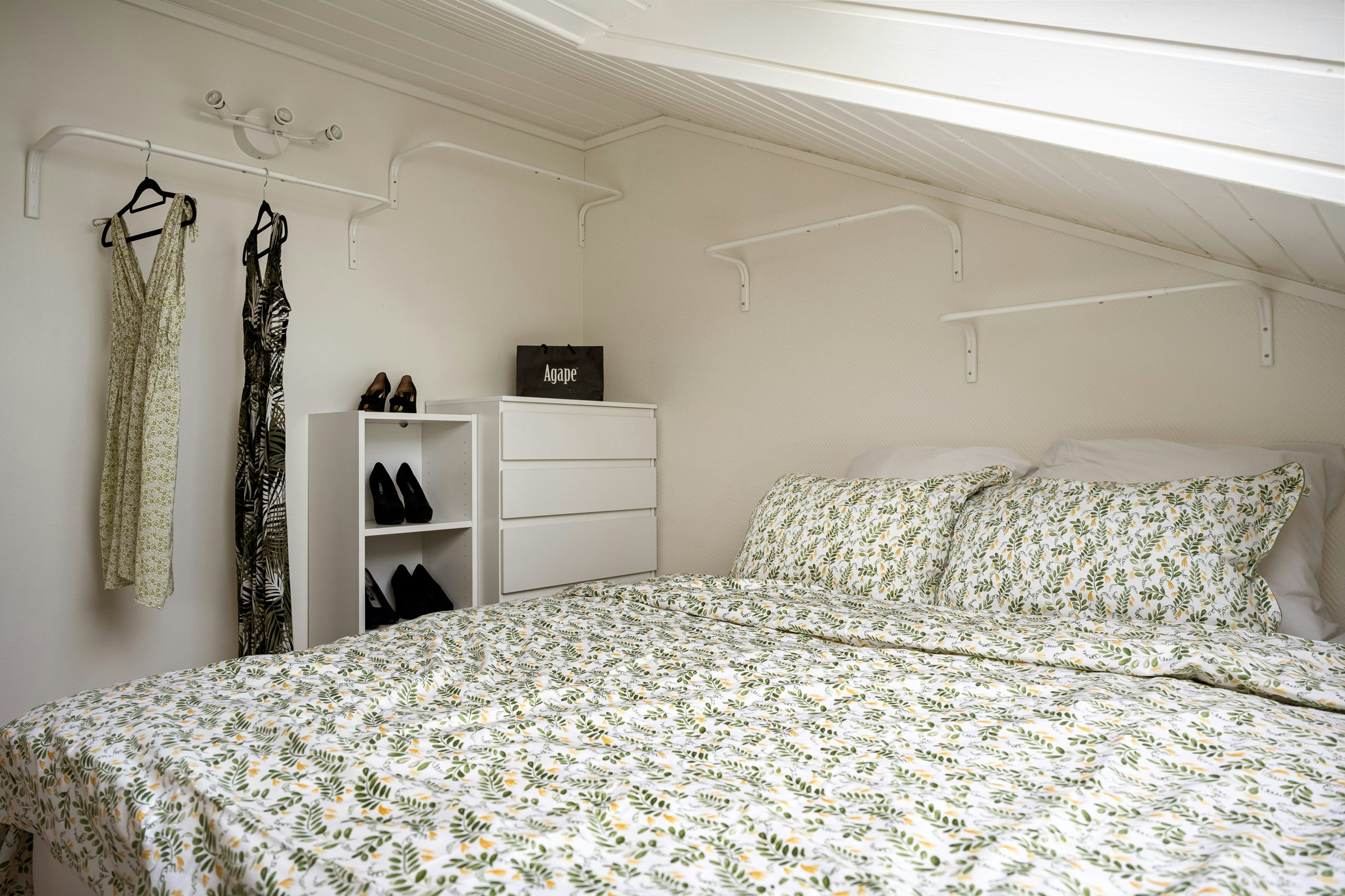 A bed sitting under a window next to a white dresser