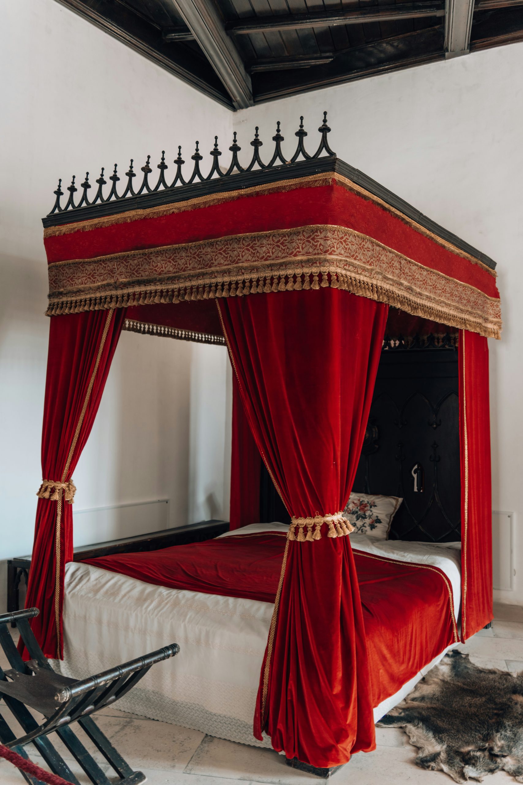 a bed with a red canopy and a black iron headboard