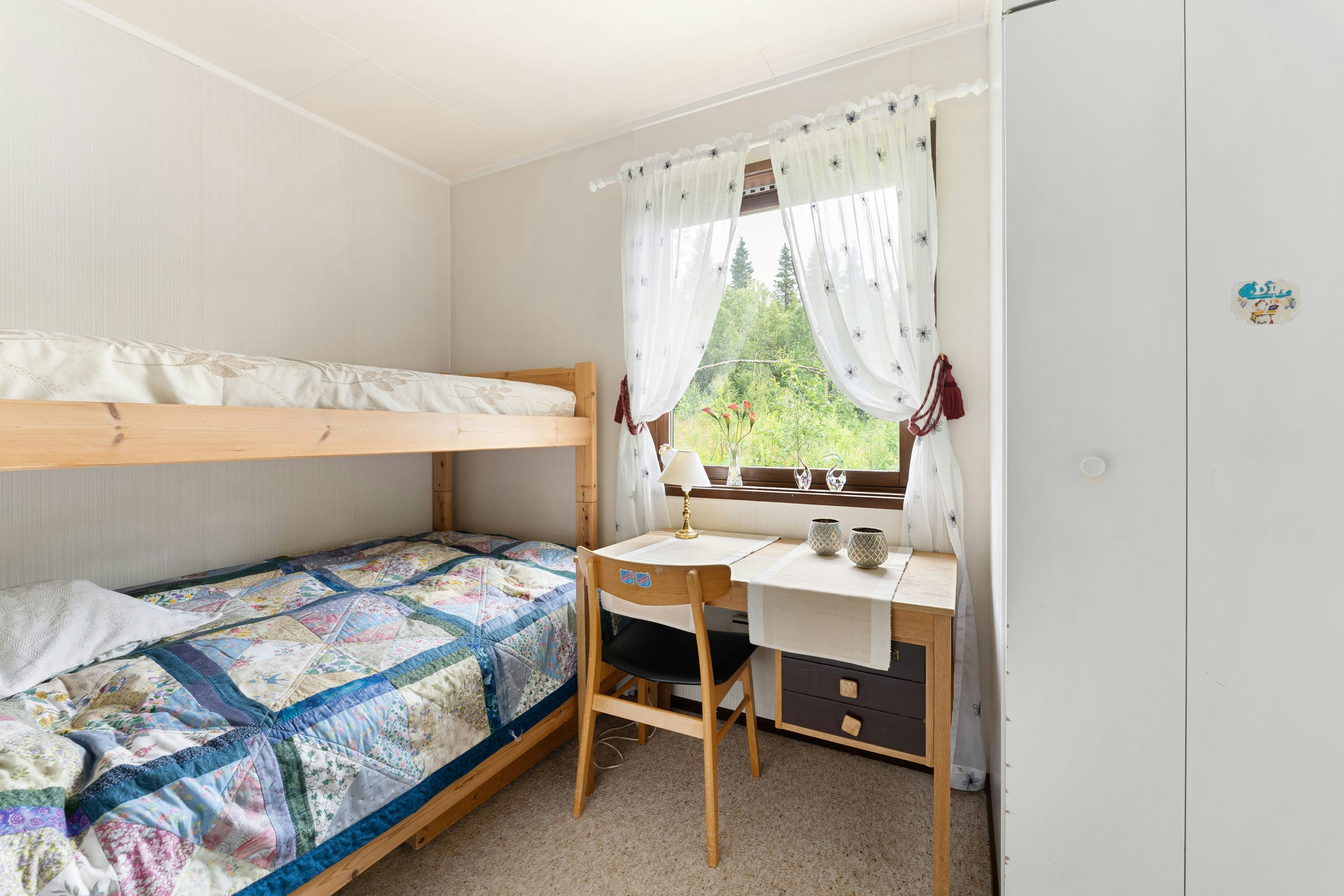 A bedroom with two bunk beds and a desk