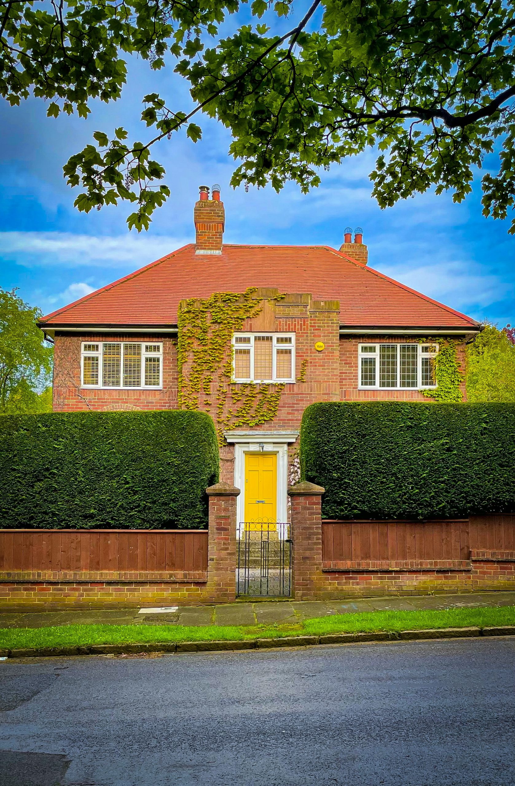 A brick house with a red roof and yellow door.