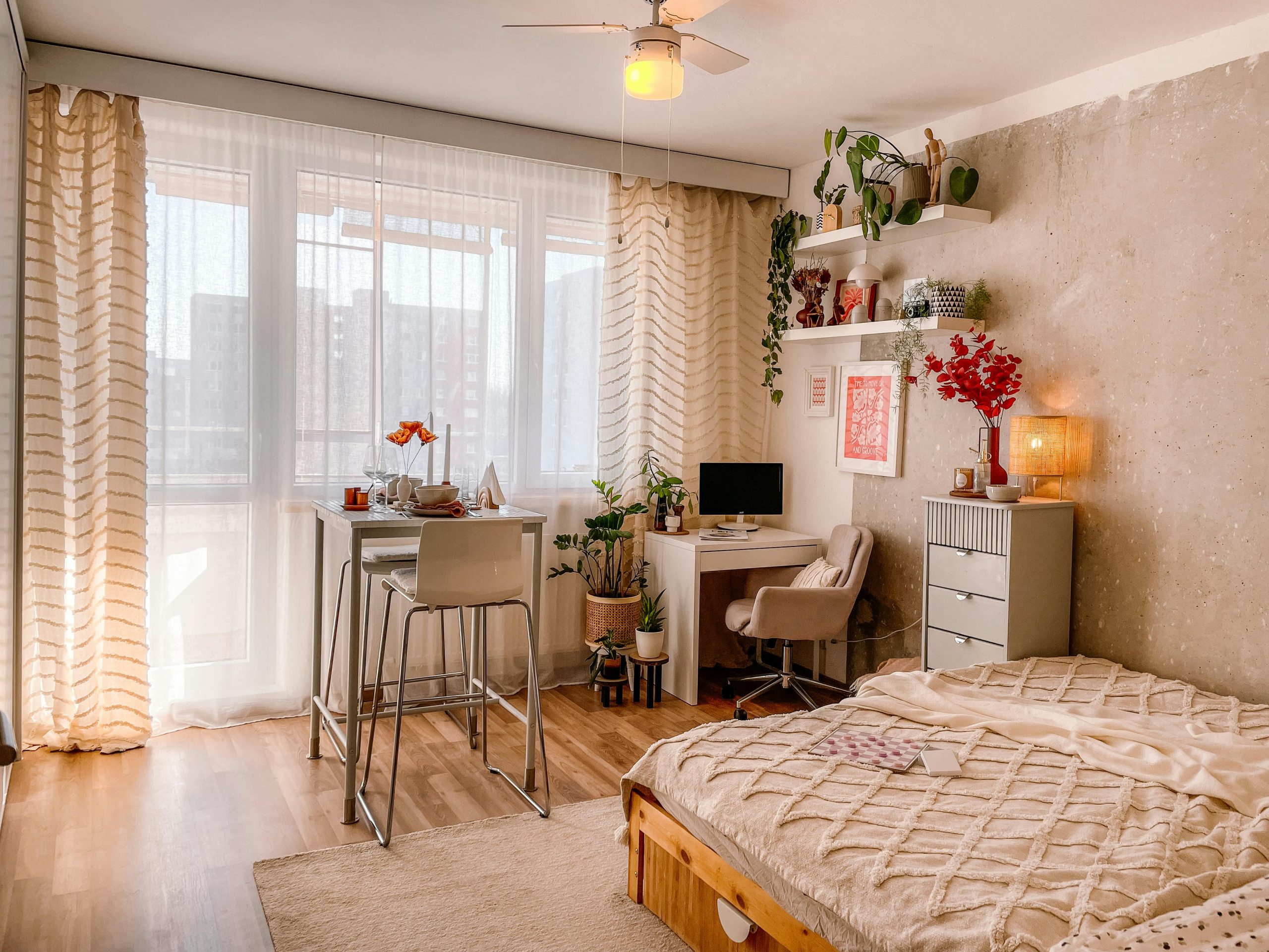 A bright and cozy Scandinavian-style bedroom with wooden floors, plants, and modern furnishings.