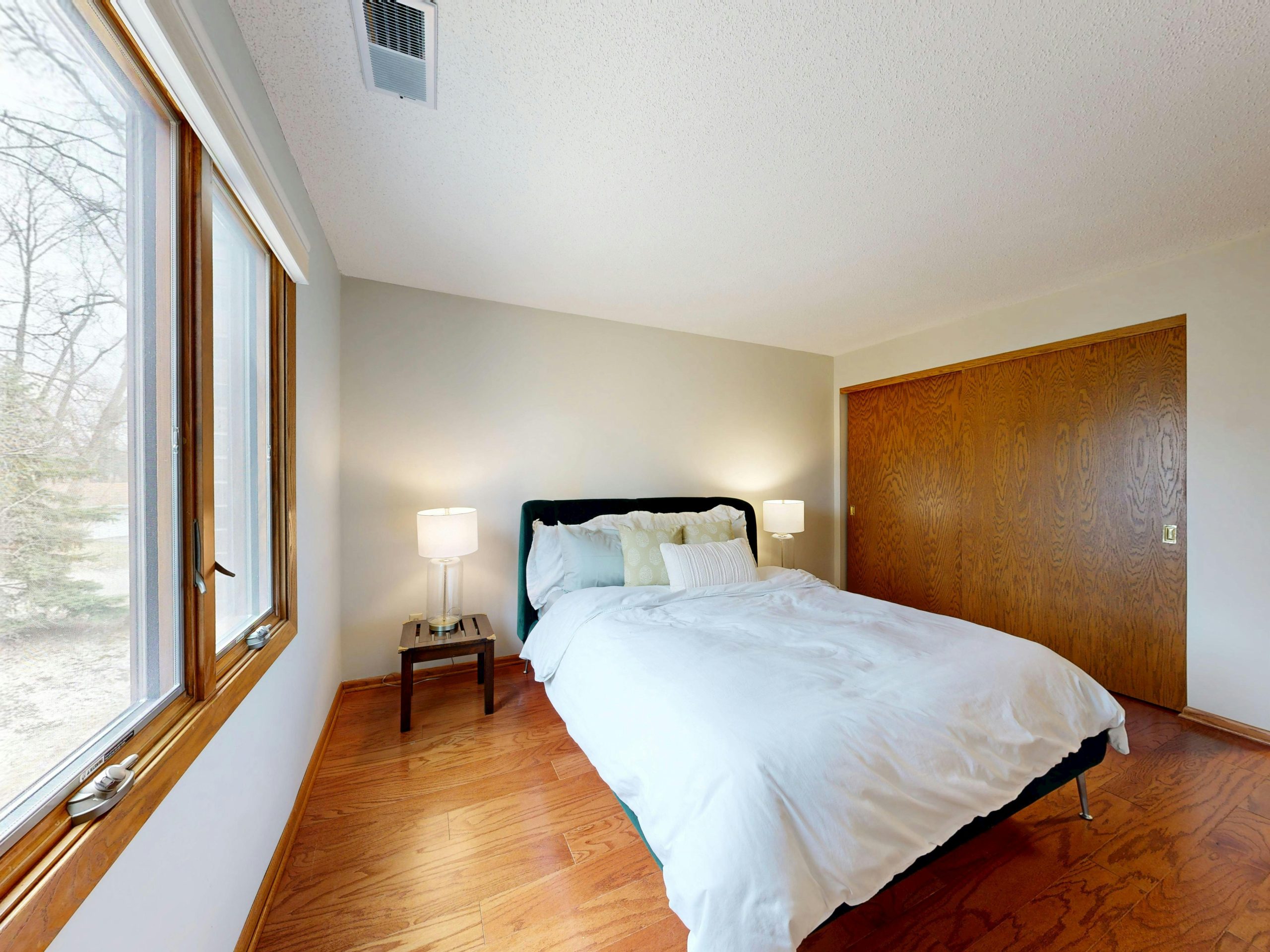 A clean and modern bedroom interior with a comfortable bed and wooden flooring.