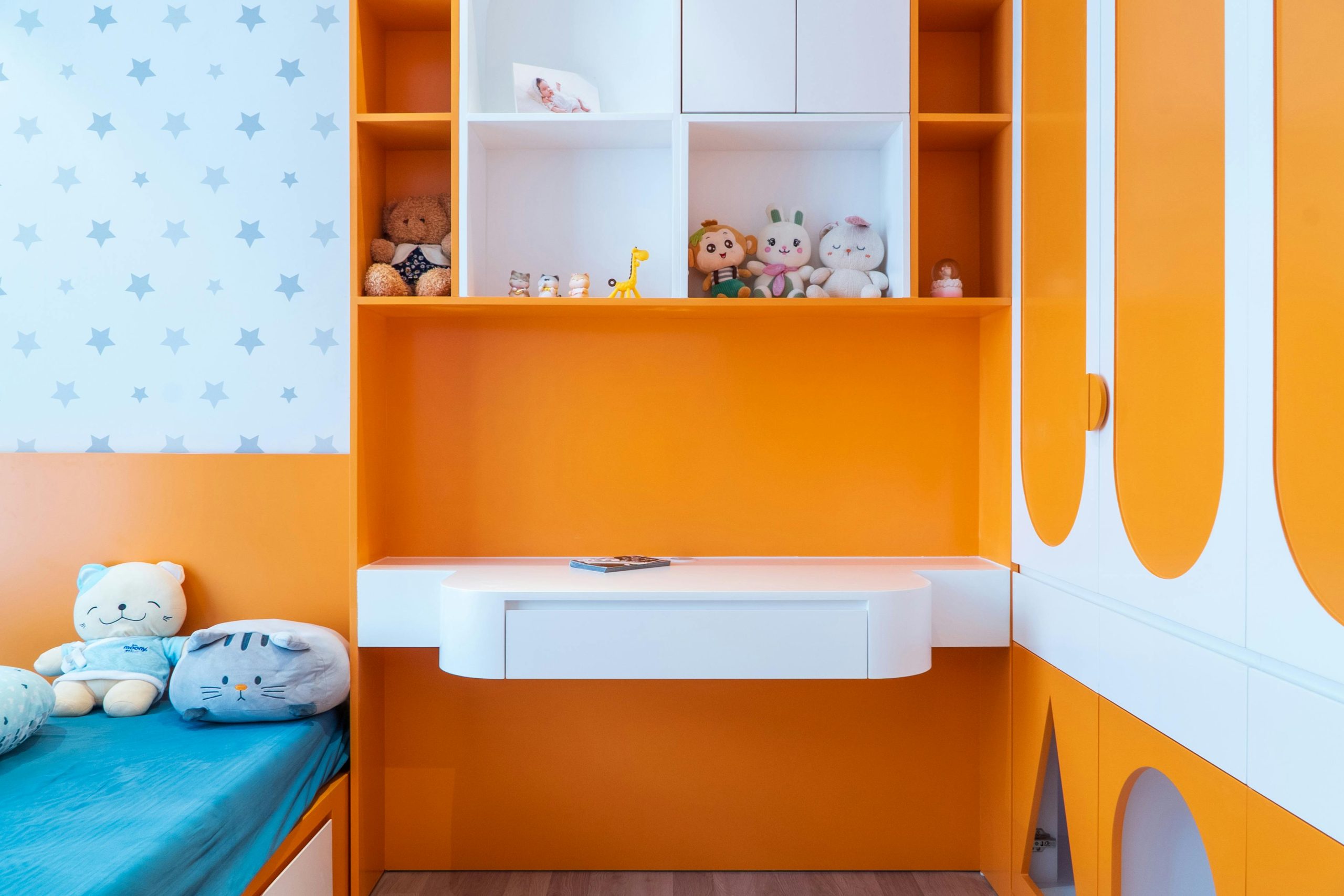 A colorful children's bedroom featuring orange decor and plush toys, creating a playful ambience.