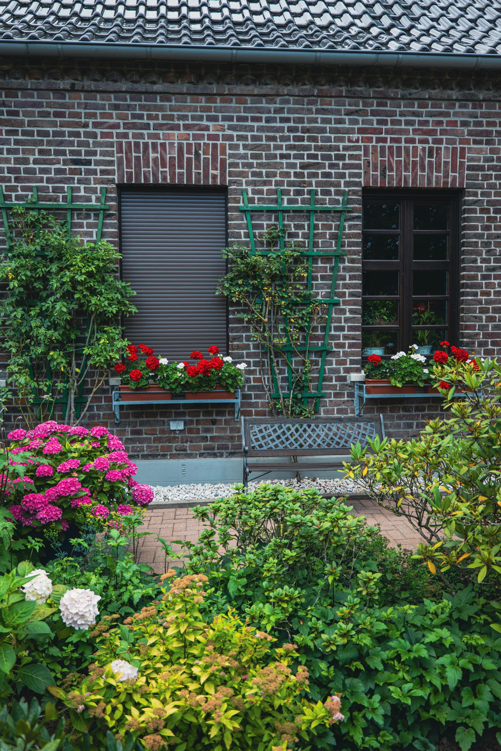 A delightful garden with colorful flowers against a rustic brick house providing a serene and inviting atmosphere.