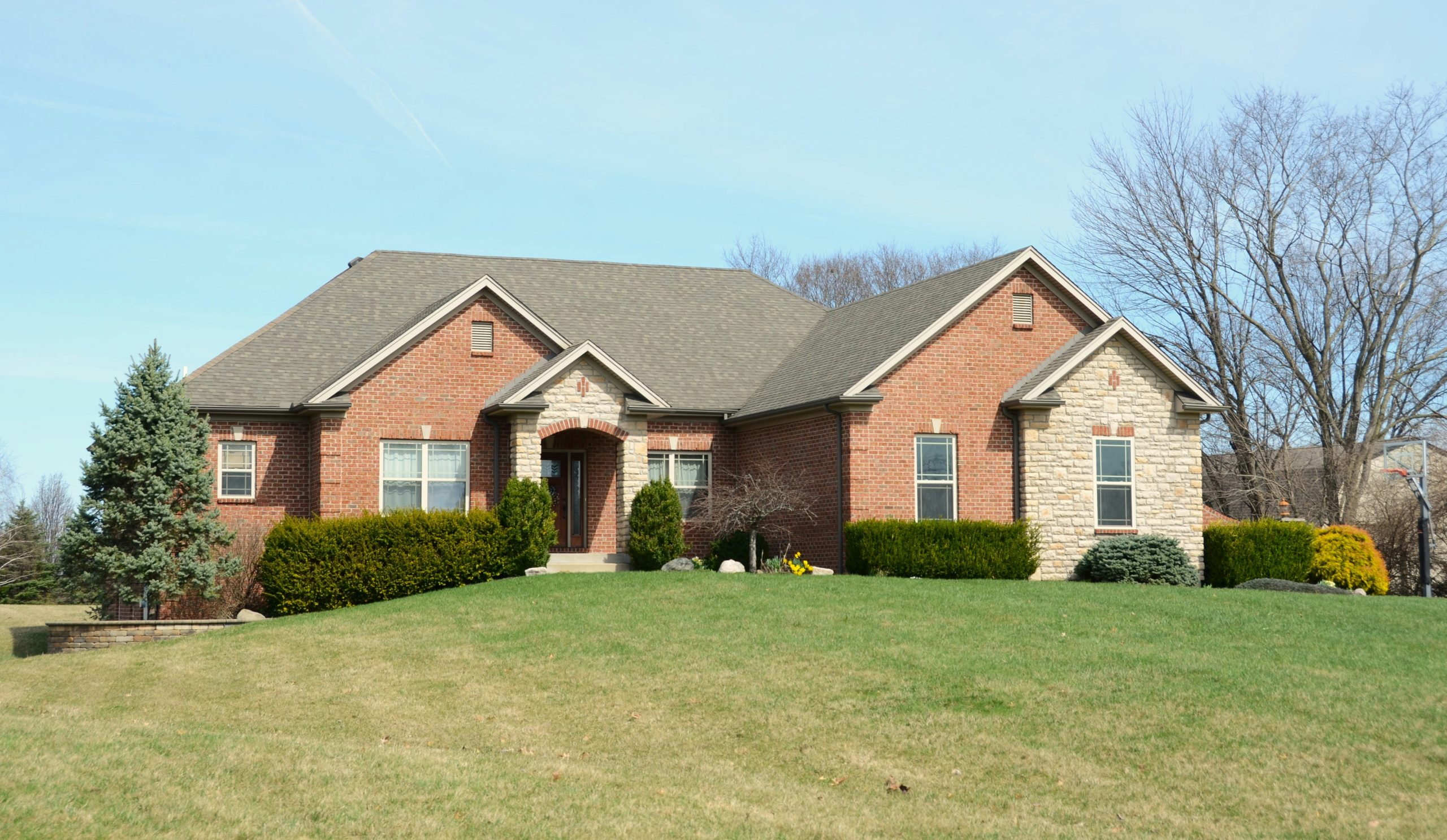 A large brick house with a manicured lawn.
