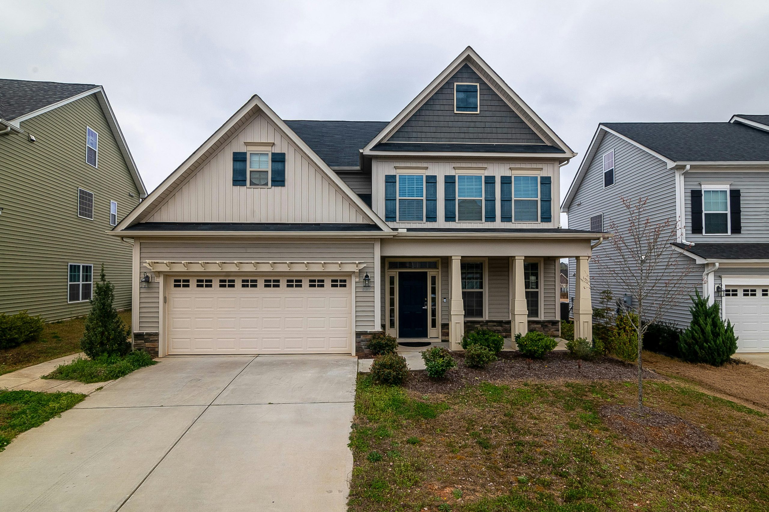 A modern two-story family home with a garage and landscaped yard in a suburban setting.