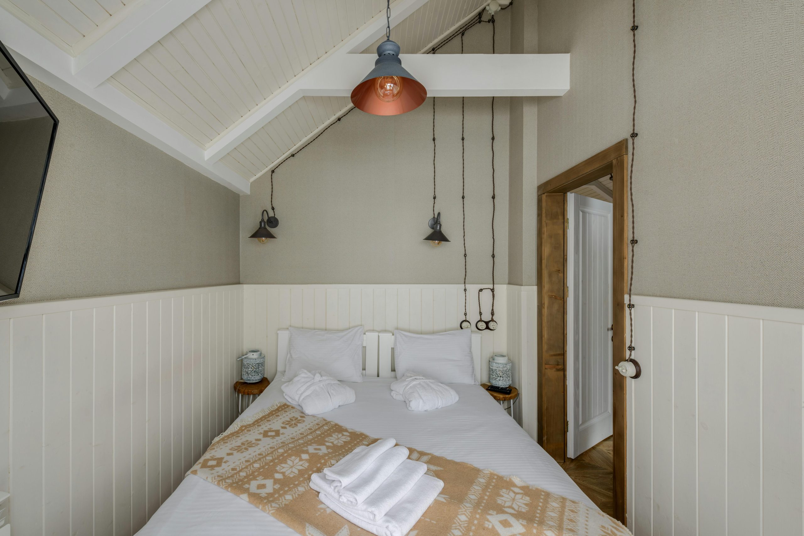 A serene Scandinavian-style bedroom featuring minimal decor and modern pendant lights.