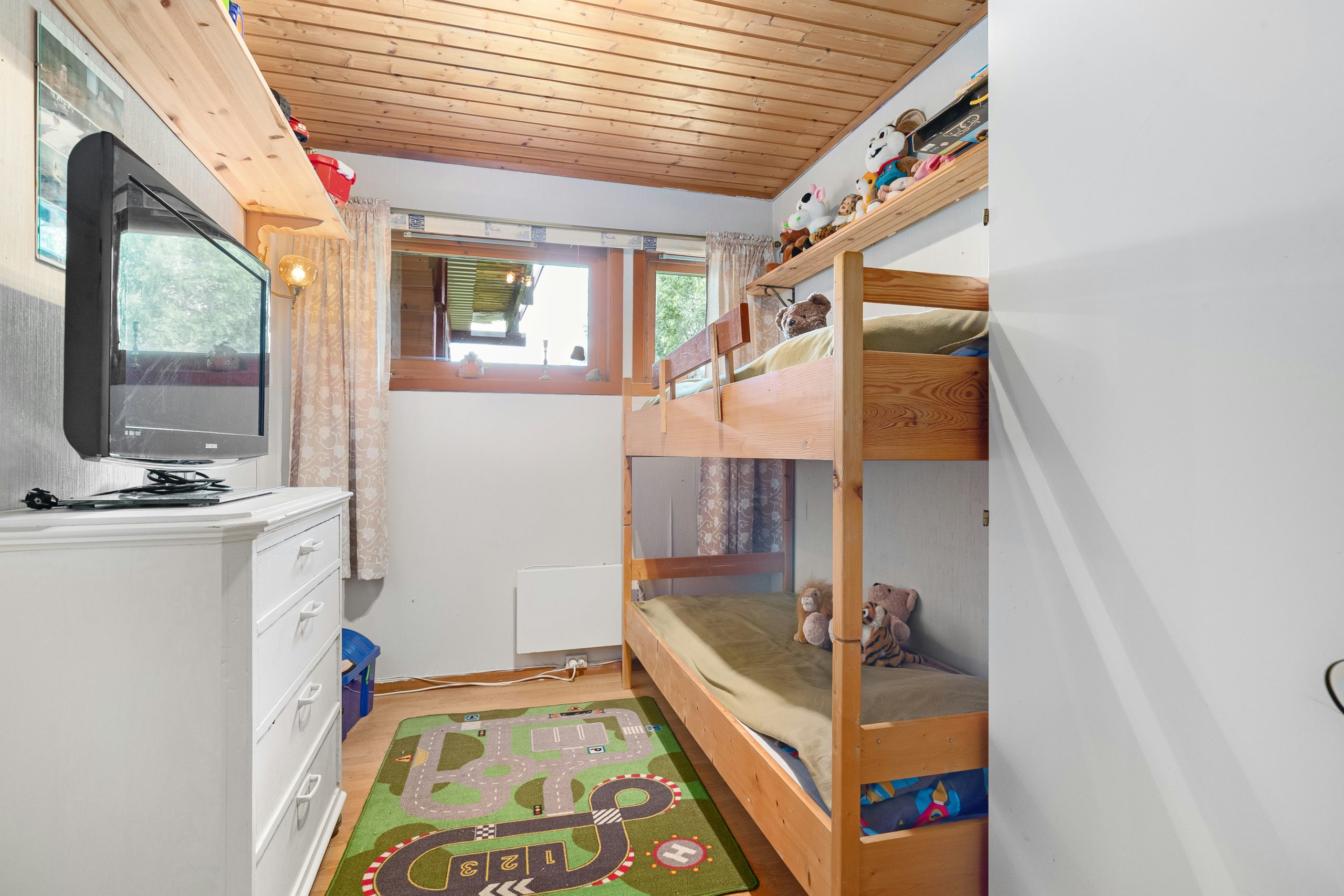 A small room with bunk beds and a flat screen TV