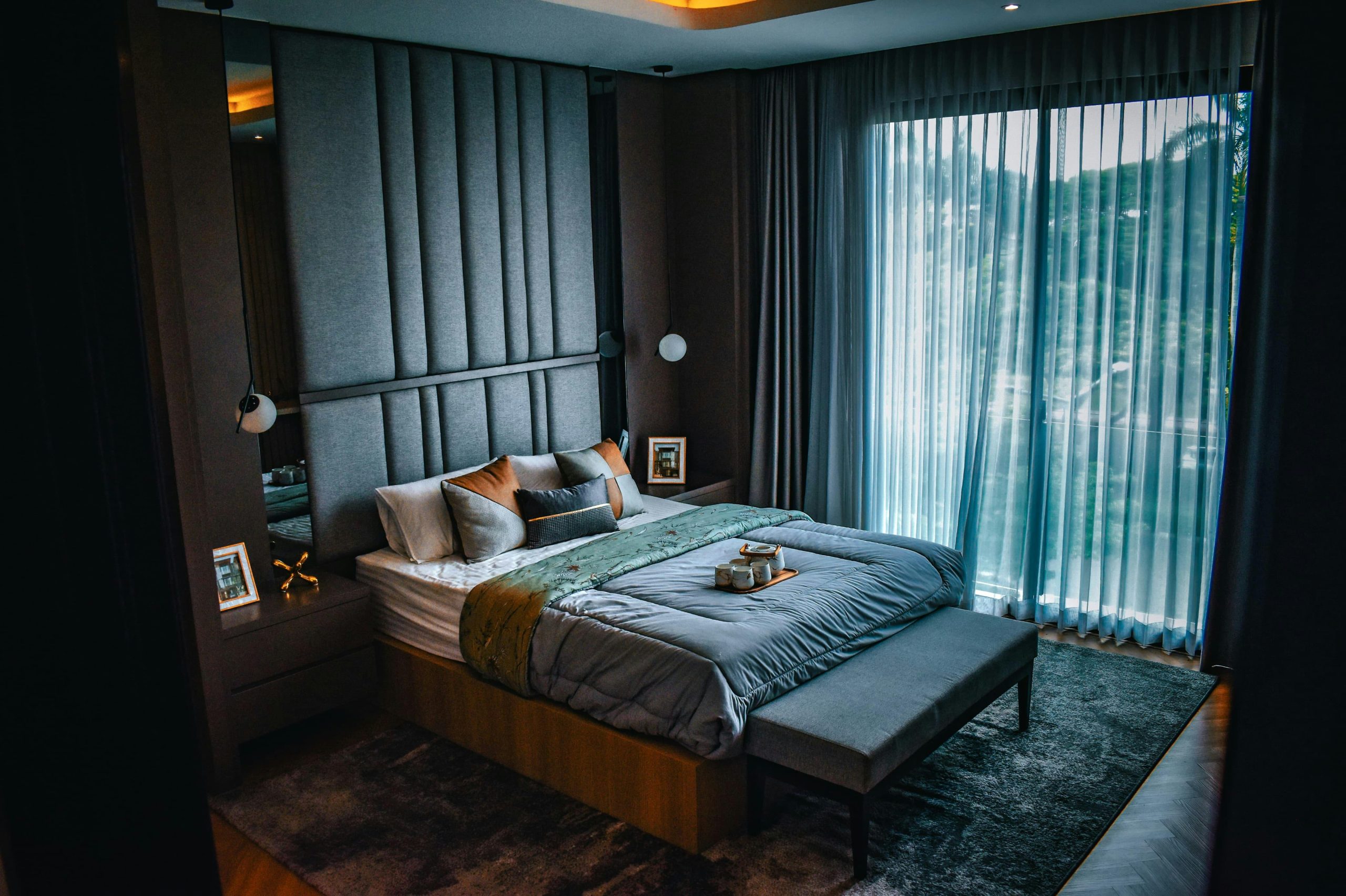 A spacious, modern bedroom with elegant decor and a large window.
